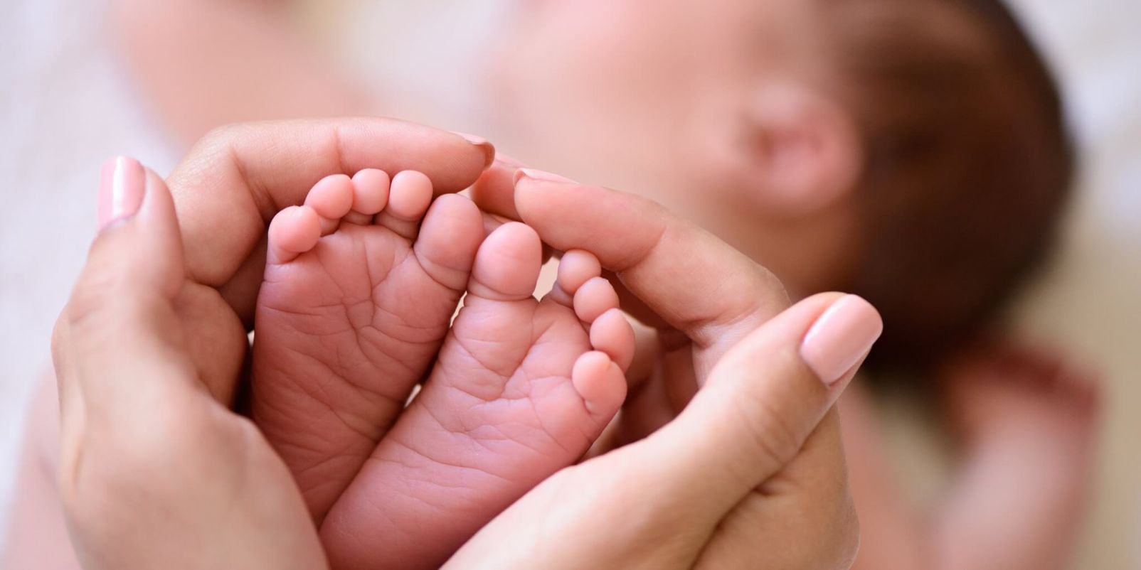 Mother holding tiny foot of newborn baby
