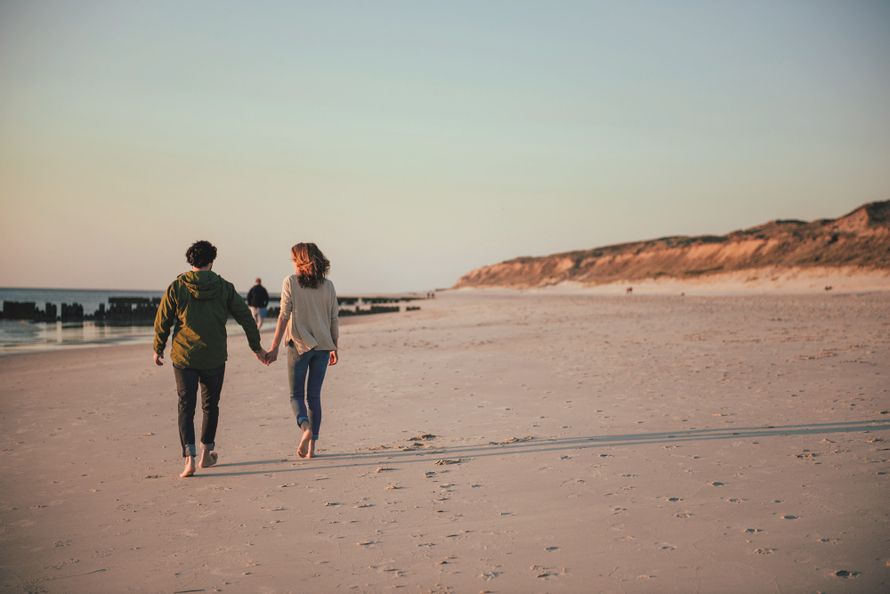 Paar spaziert am Strand vor dem Roten Kliff