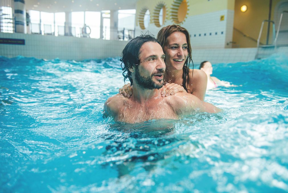 Mann und Frau warten auf die nächste Welle im Wellenbecken der Sylter Welle