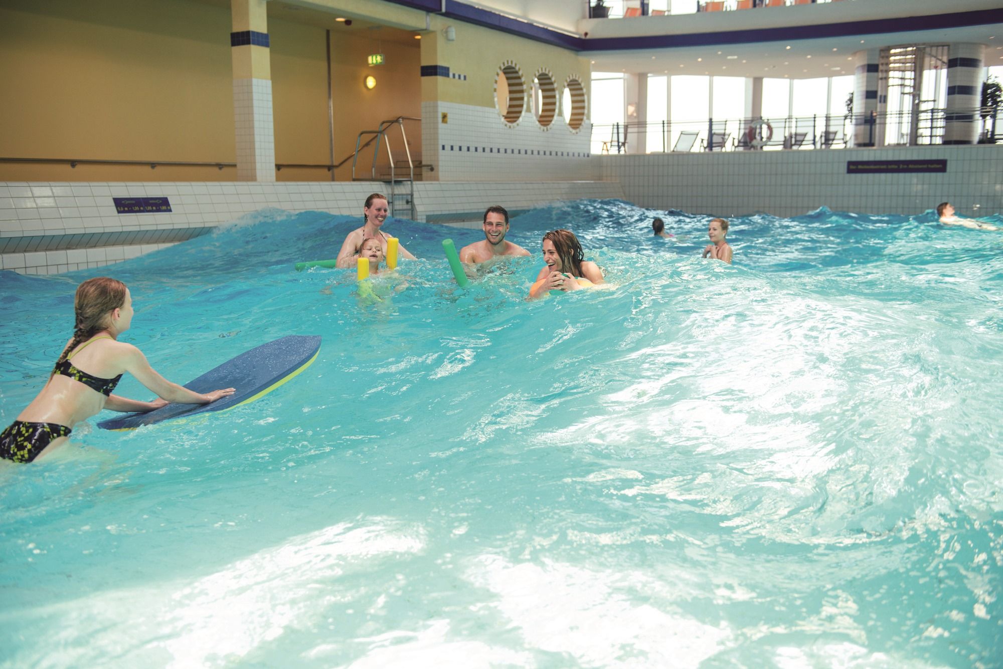 mehrere Personen schwimmen in den Wellen im Wellenbecken in der Sylter Welle