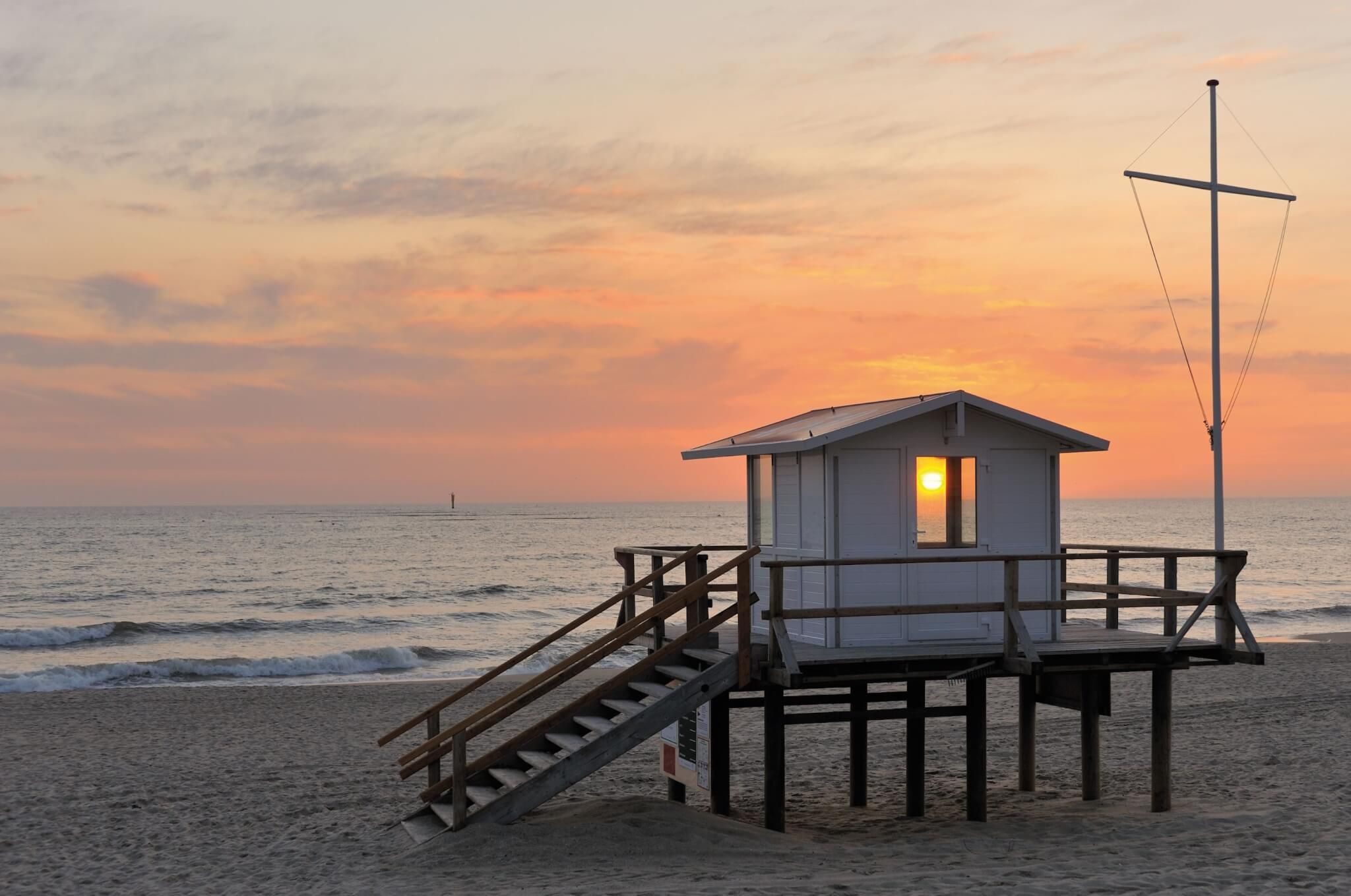 Sonnenuntergang scheint durch die Fenster eines Rettungsschwimmerstandes in Rantum auf Sylt