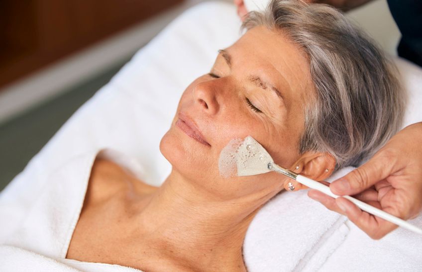 Frau bekommt mittels Pinsel eine Creme auf das Gesicht aufgetragen bei einer Gesichtsbehandlung im Syltness Center
