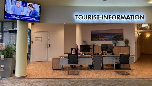 Mitarbeiter sitzt am Schreibtisch in der Tourist-Information im Syltness Center