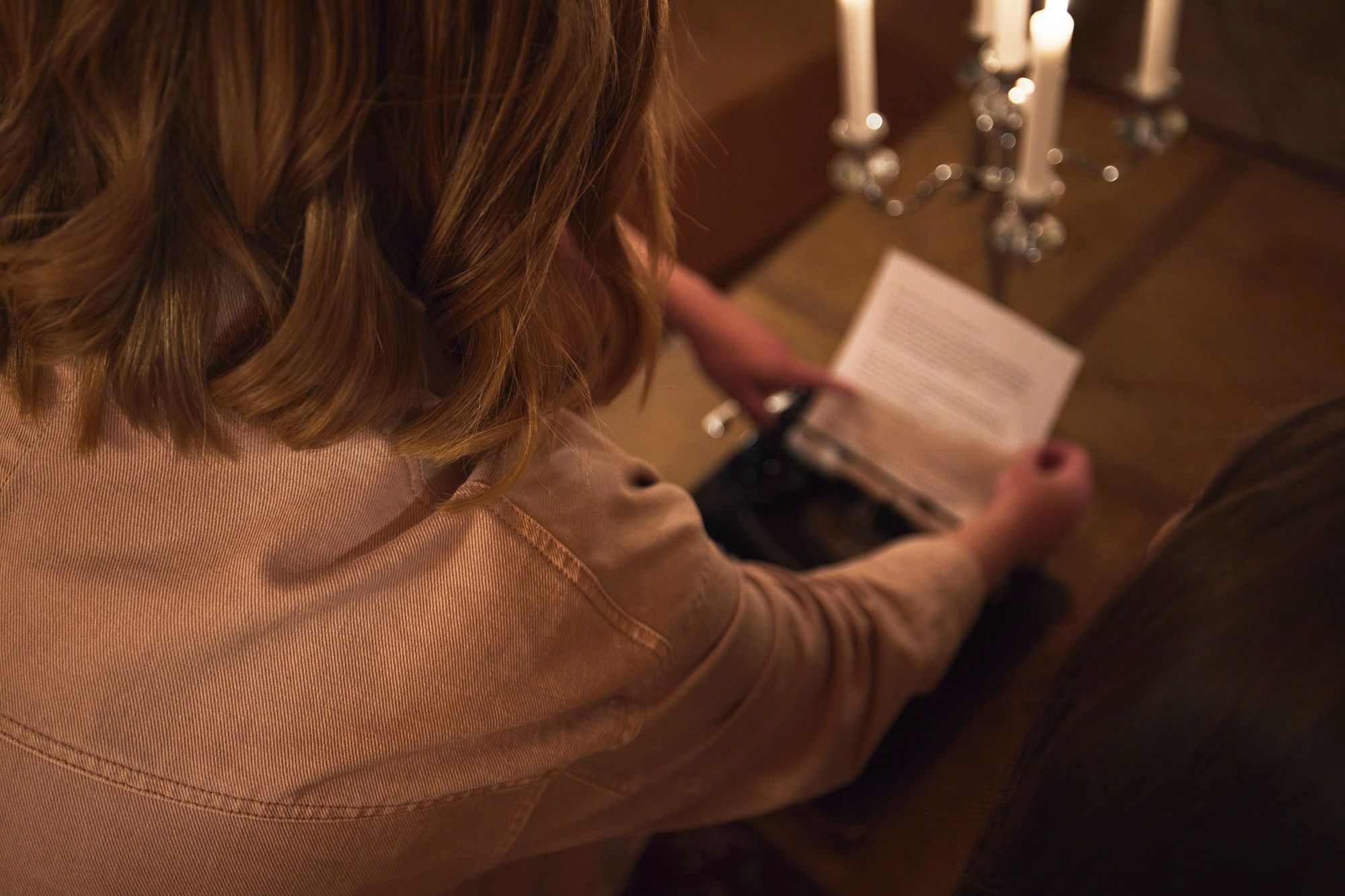 Junge Frau liest Text auf einem in eine nostalgische Schreibmaschine gespannten Blatt