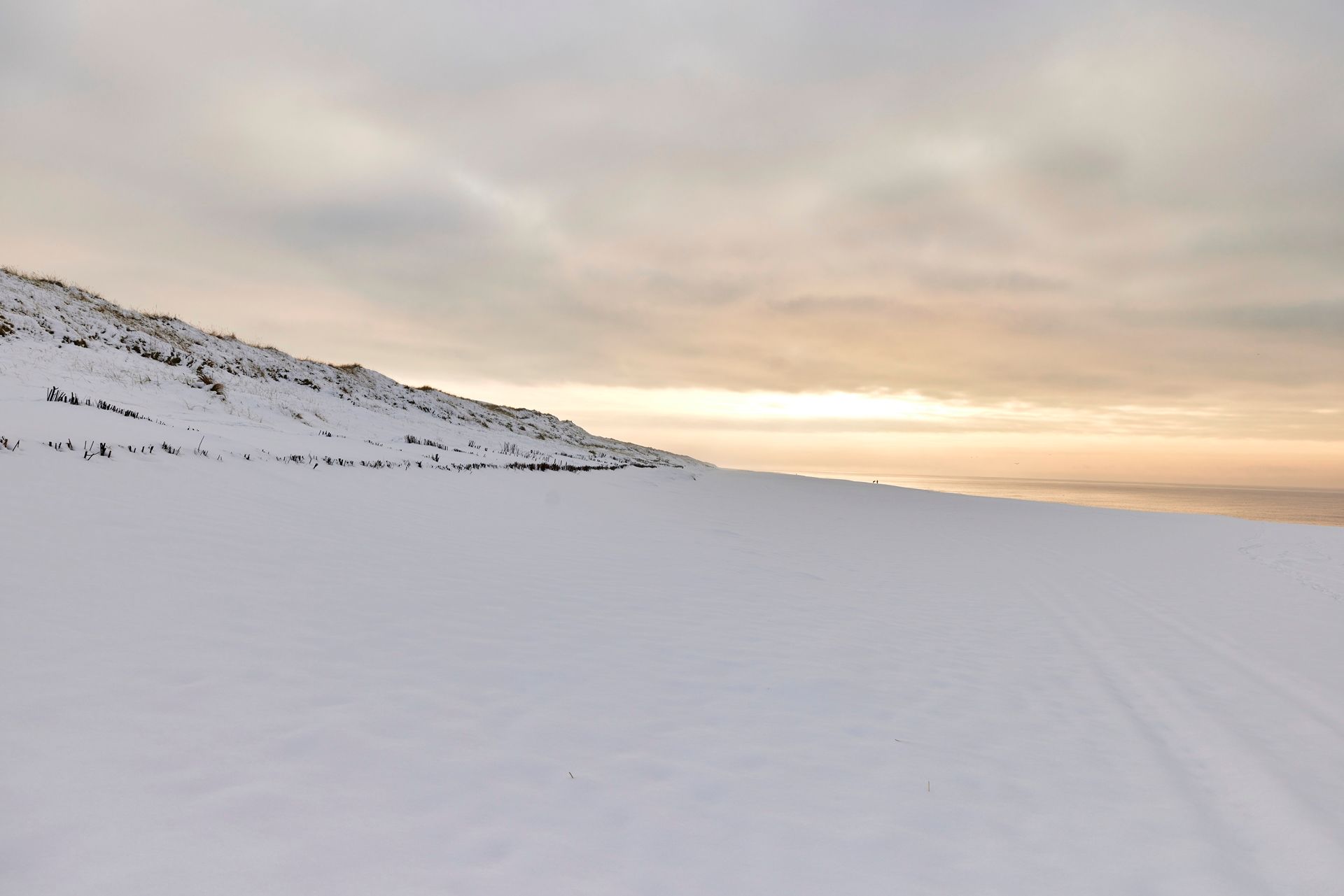 Strand mit Schnee bedeckt und Sonnenuntergang im Hintergrund
