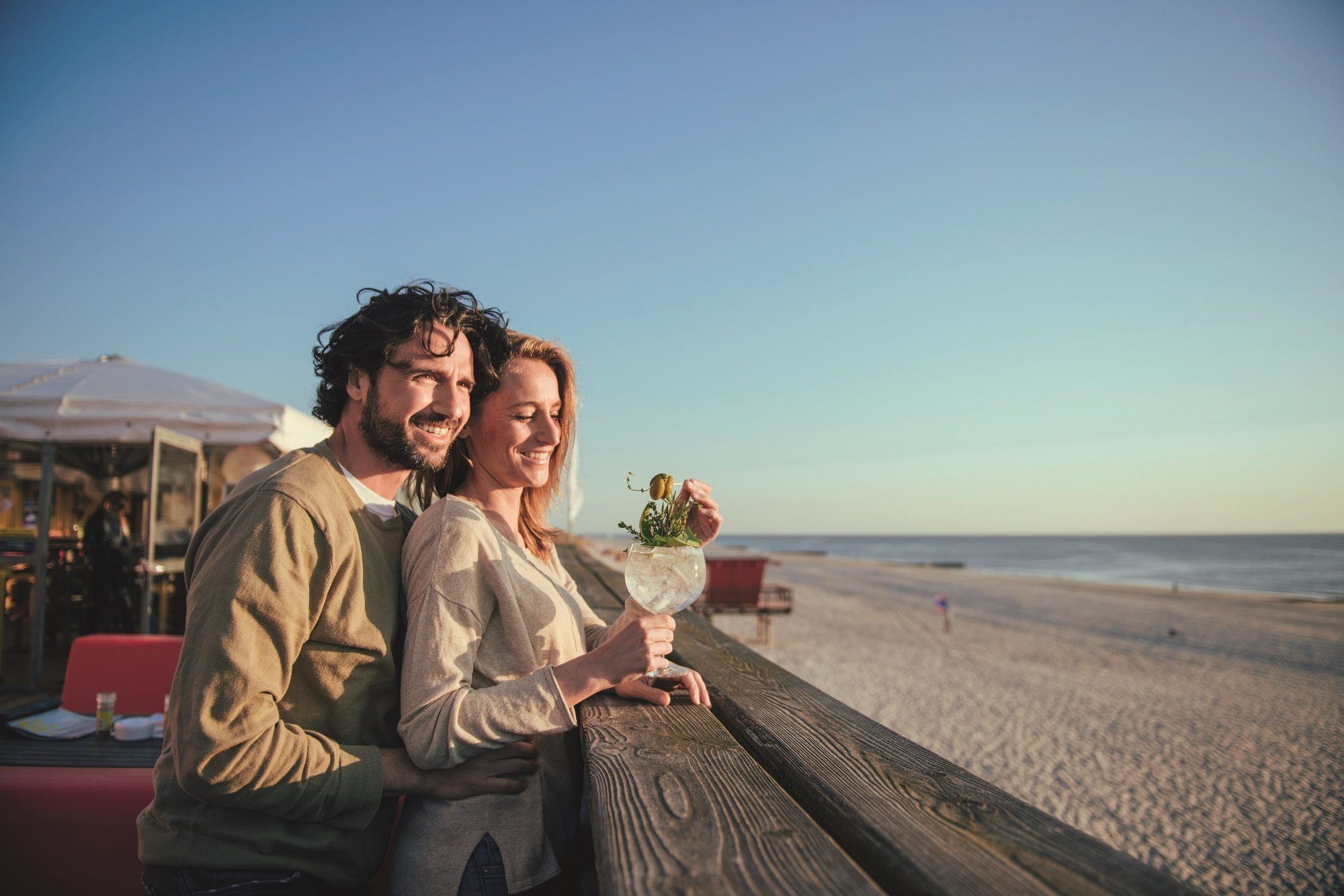 Mann steht hinter Frau und blicken gemeinsam von der Promenade auf die Nordsee