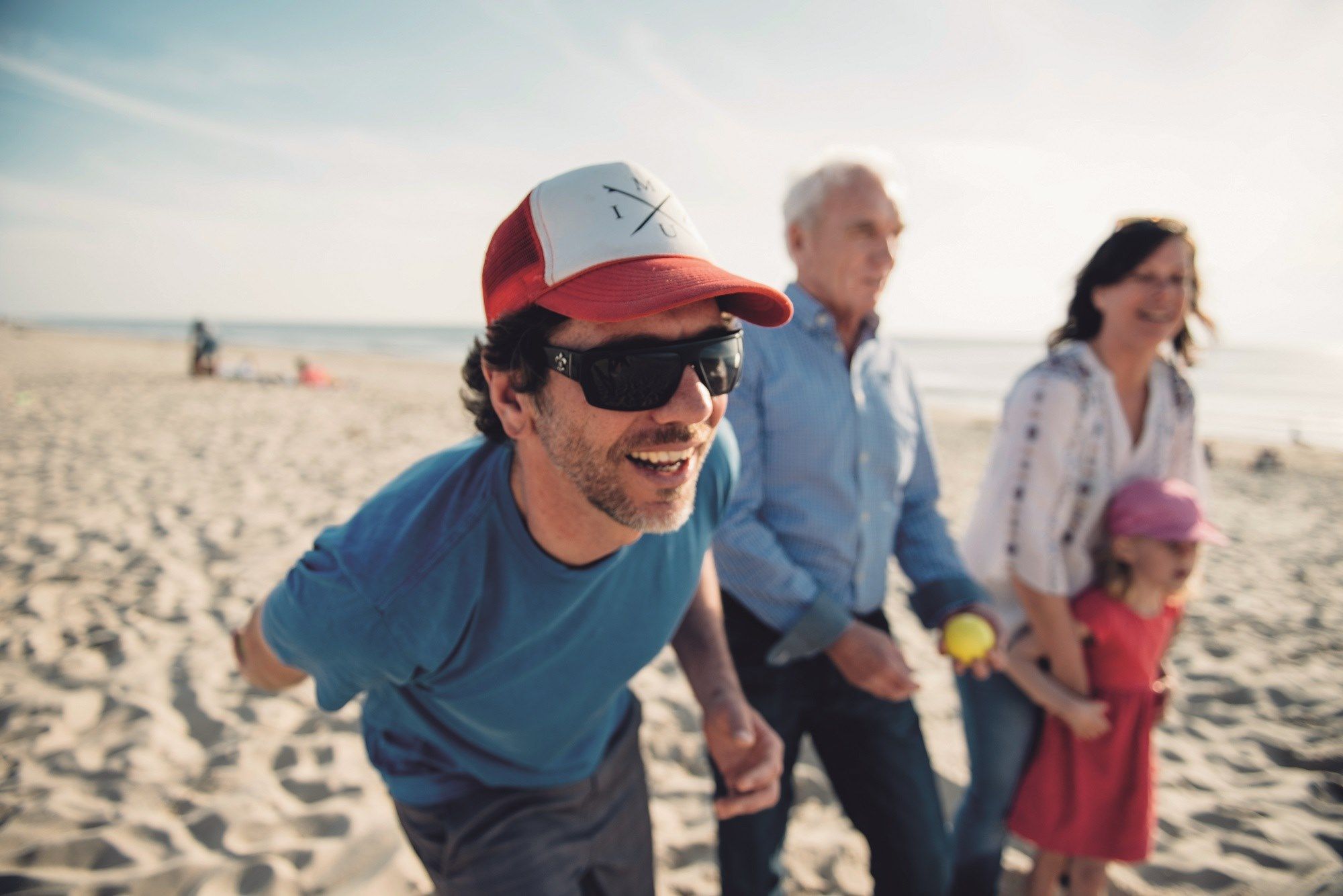 Mann mittleren Alters spielt mit Frau, älterem Mann und Mädchen Boccia am Weststrand von Westerland