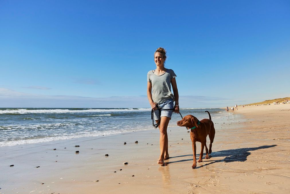 Eine Frau mit ihrem Hund am Hundestrand