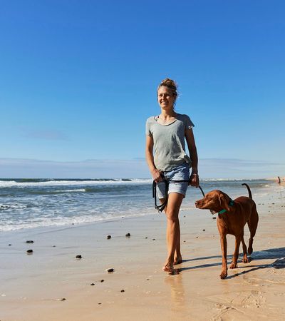 Eine Frau mit ihrem Hund am Hundestrand
