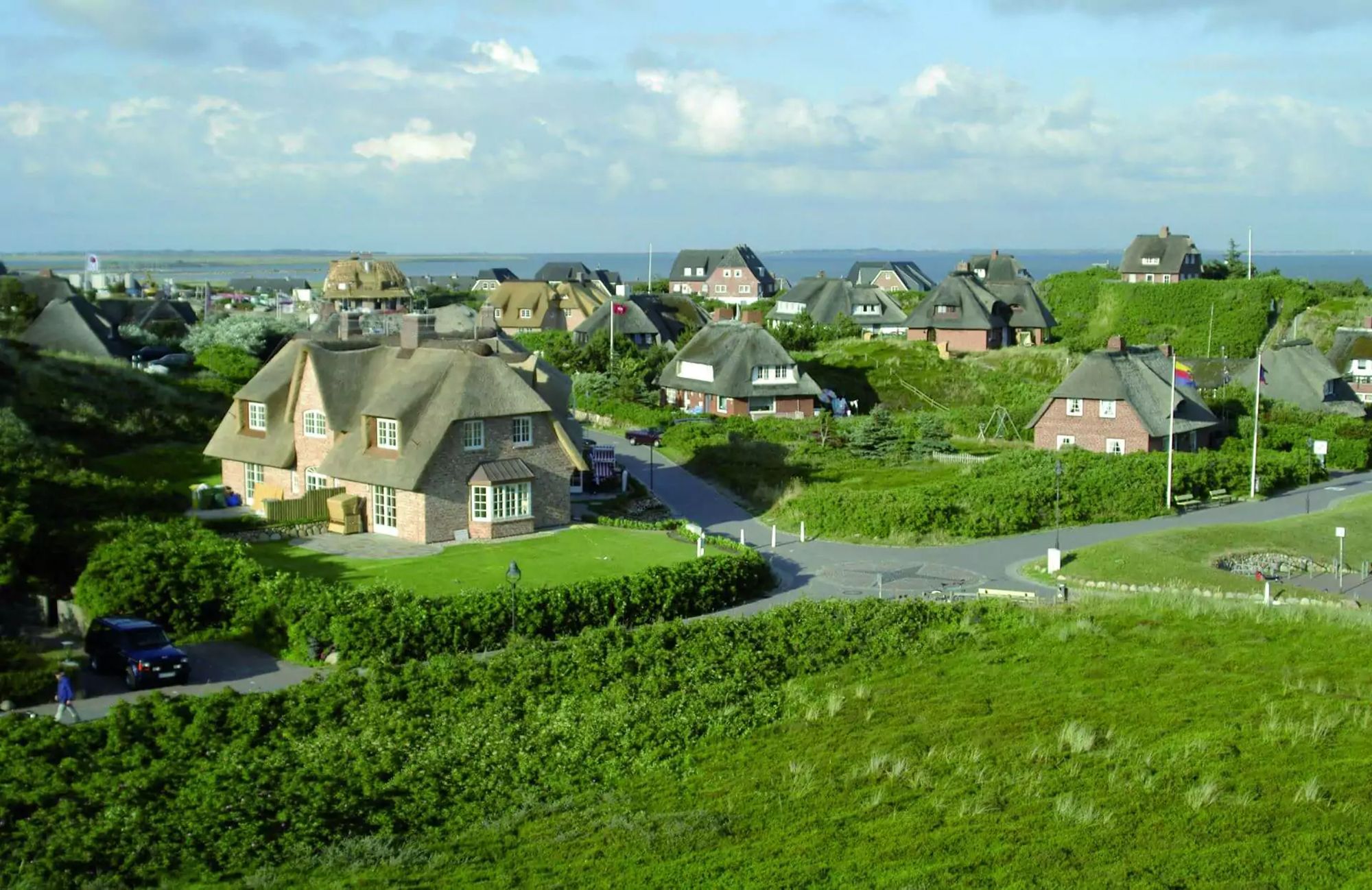 Blick auf das Dorf Rantum auf Sylt mit seinen Reetdachhäusern, im Hintergrund die Nordsee