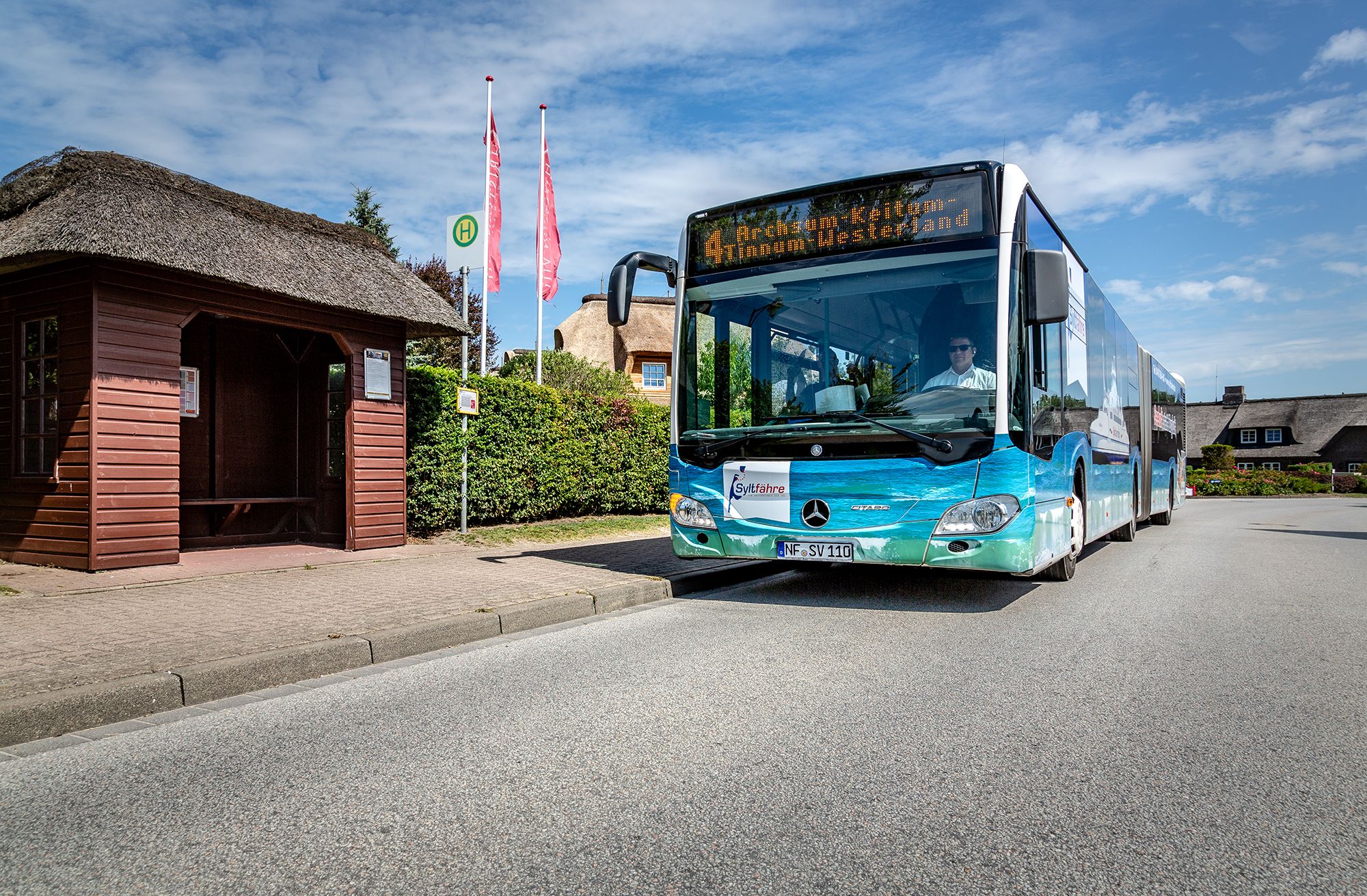 Linienbus der Sylter Verkehrsgesellschaft vor einer reetgedeckten Bushaltestelle