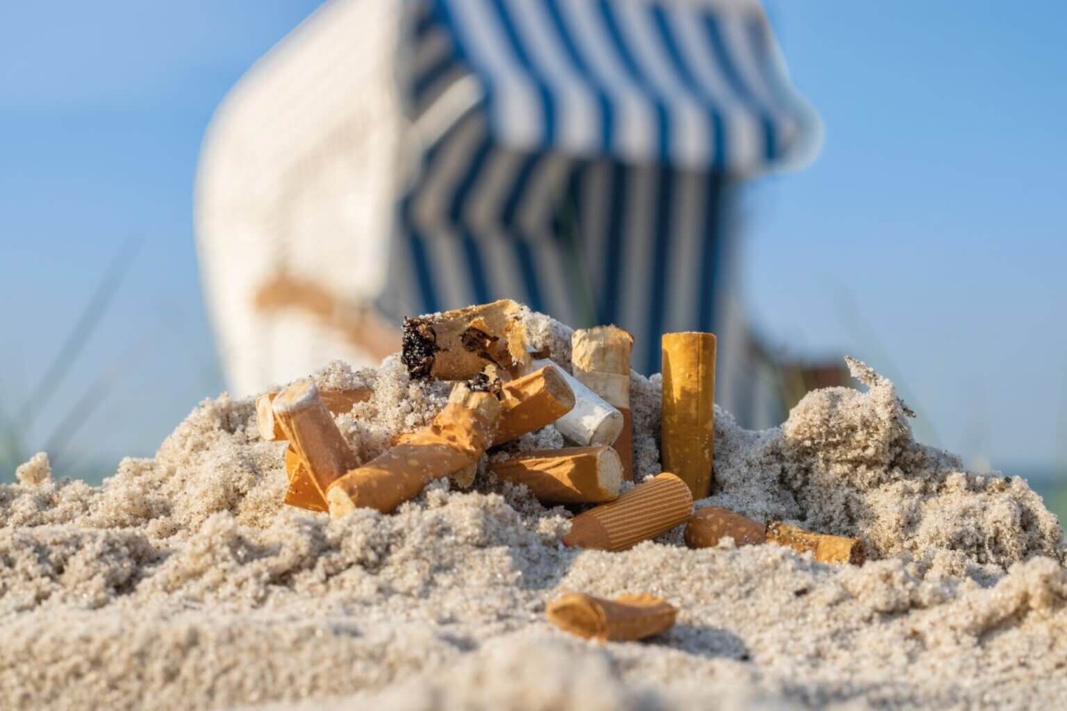 Zigarettenkippen im Sand vor einem Strandkorb