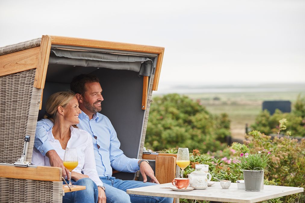 Frau und Mann sitzen im Strandkorb und trinken Orangensaft und Tee