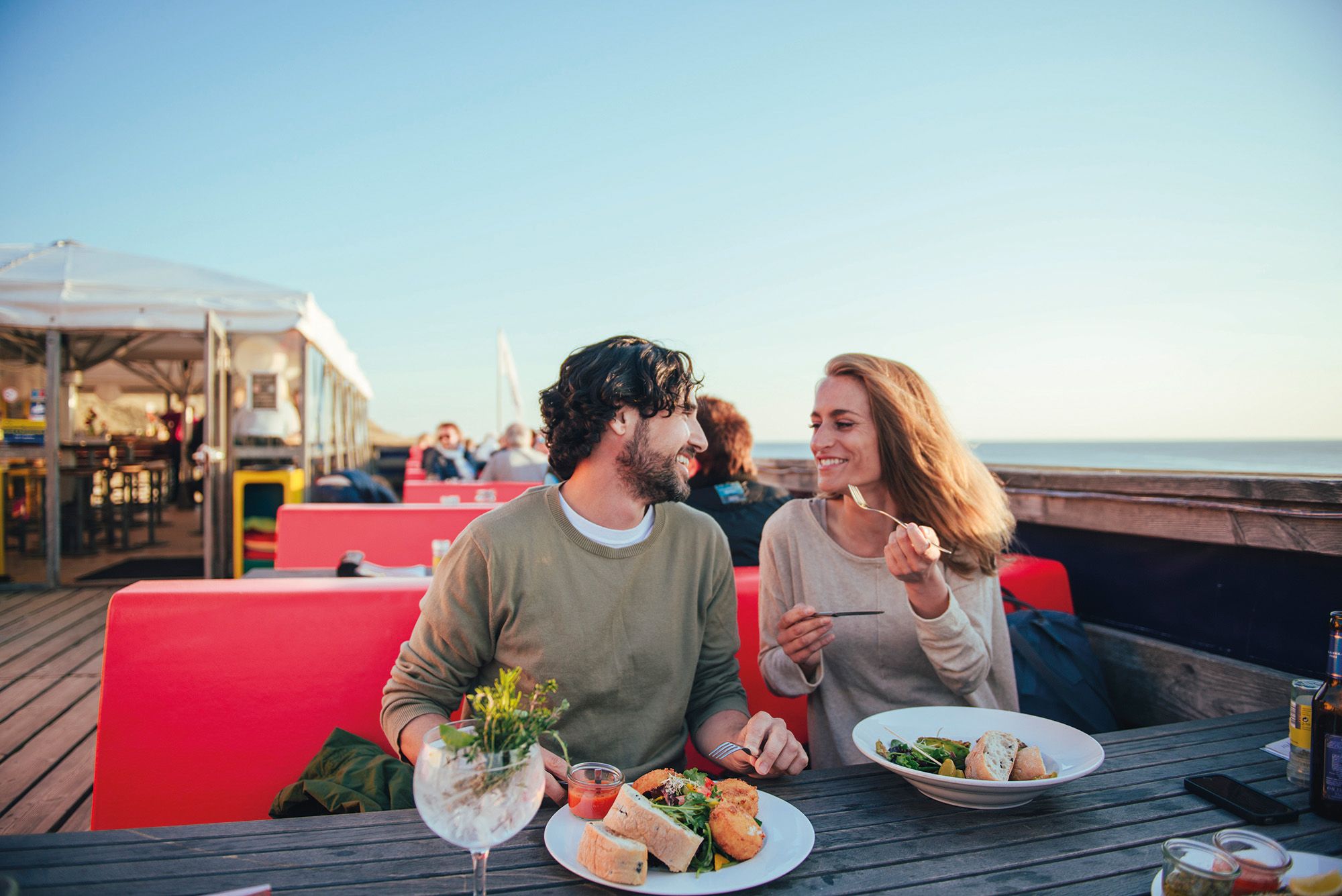 Frau und Mann sitzen auf der Terrasse eines Restaurants auf Sylt und essen
