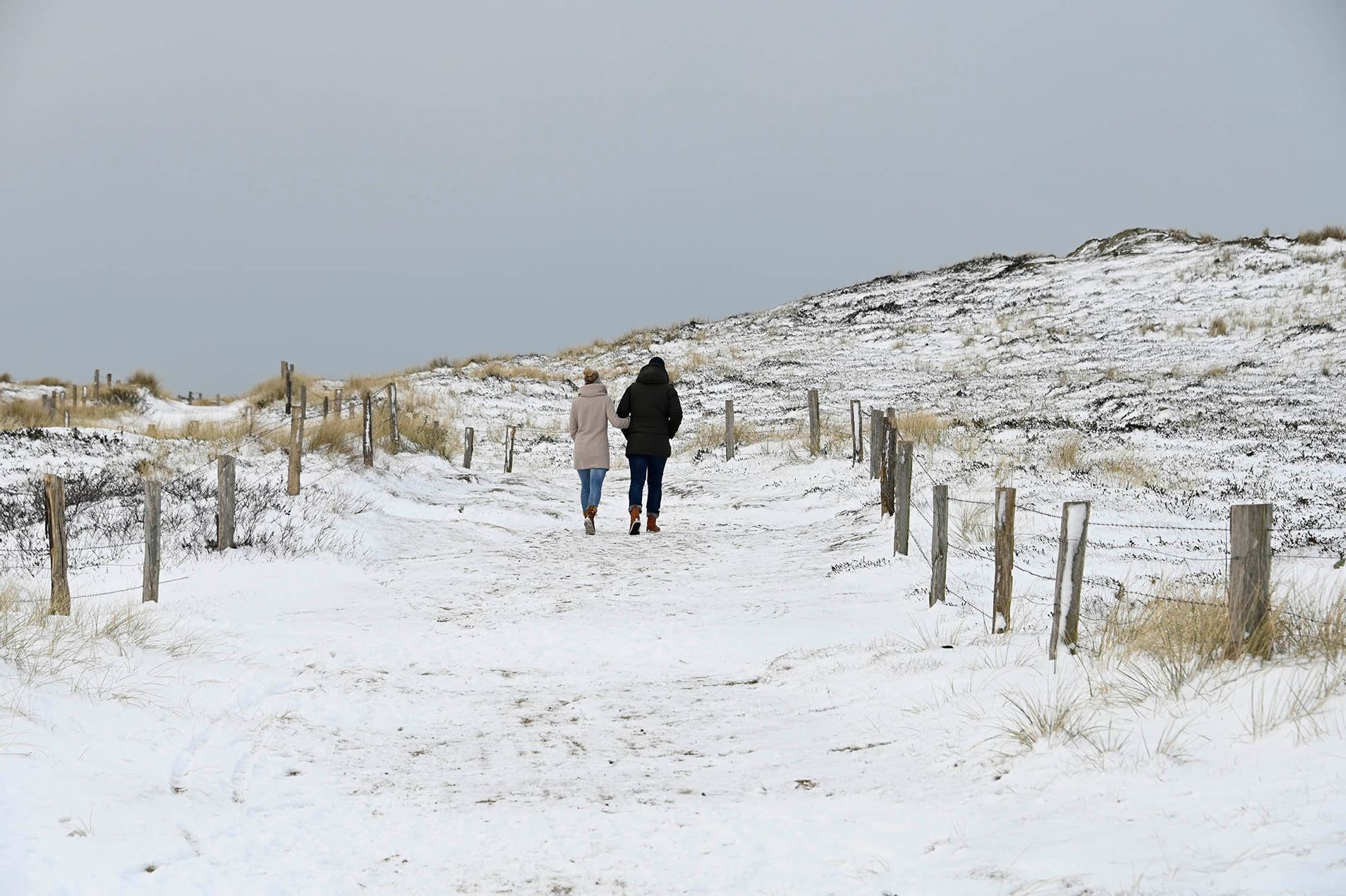 Mann und Frau spazieren durch Schneedeckte Dünenlandschaft im Süden von Westerland auf Sylt
