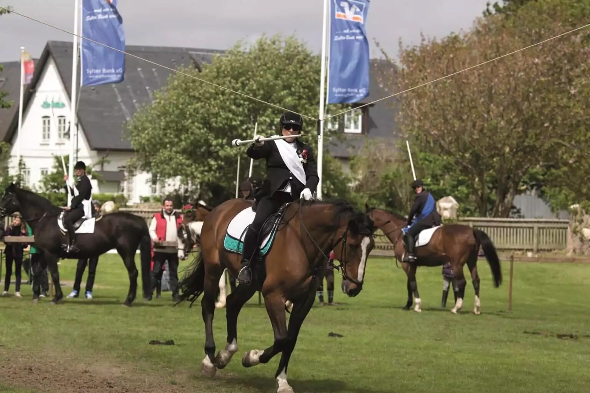 Weibliche Ringreiterin galoppiert in Archsum auf Sylt auf den Galgen zu