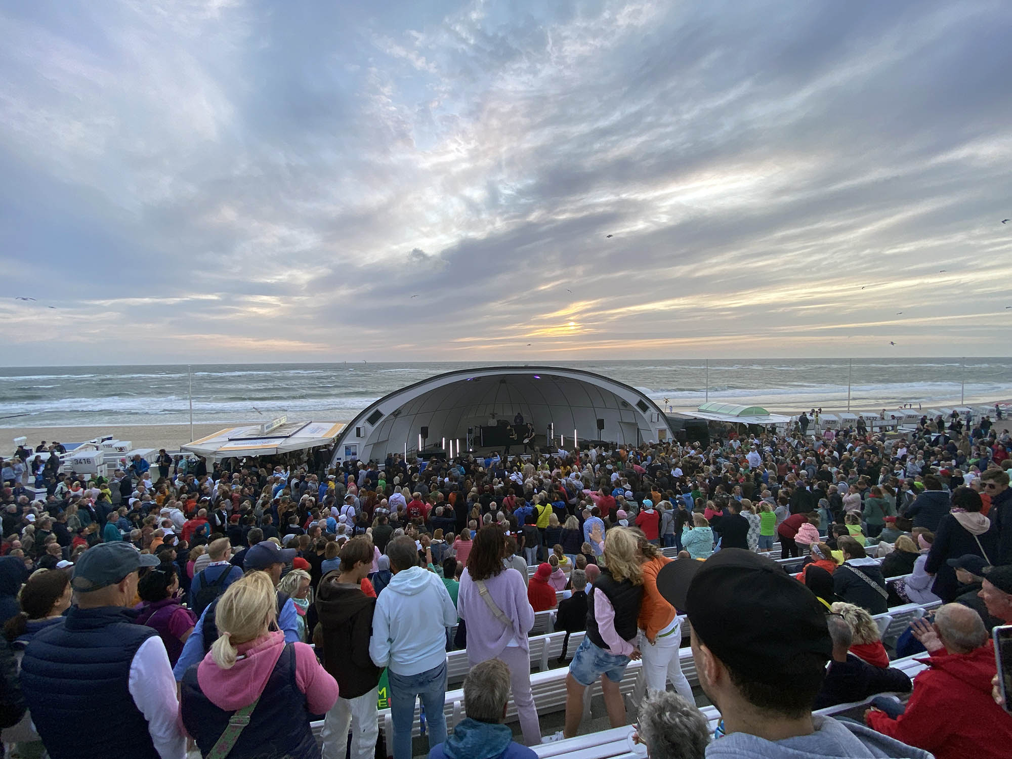 Sundowner Rhythm & Beats in der Westerländer Musikmuschel mit hunderten Besuchern davor und Sonnenuntergang dahinter