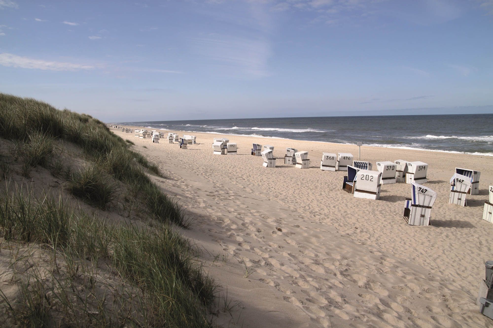 Sylter Weststrand mit Strandkörben und mit Dünengras bewachsener Düne