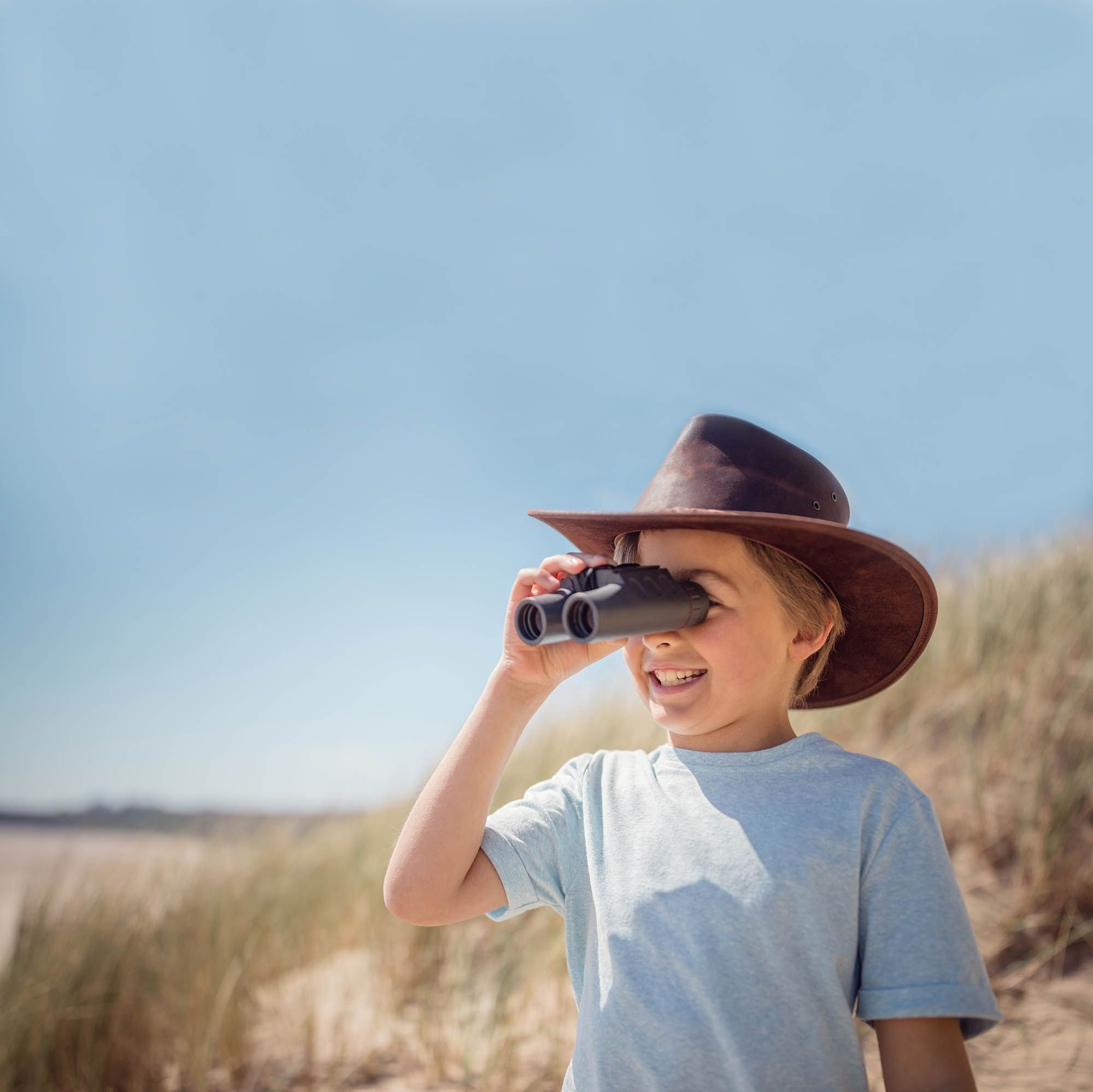 Mädchen in Entdeckeroutfit schaut durch Fernglas