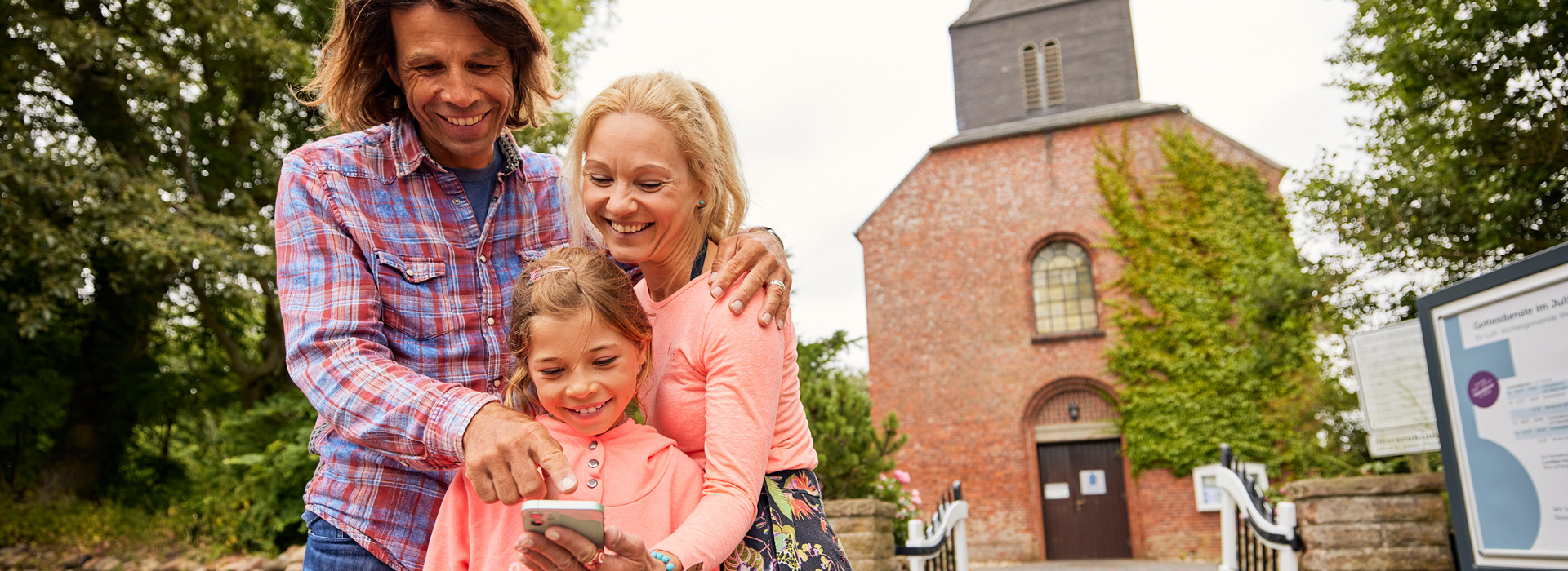 Glückliche Familie schaut auf Smartphone