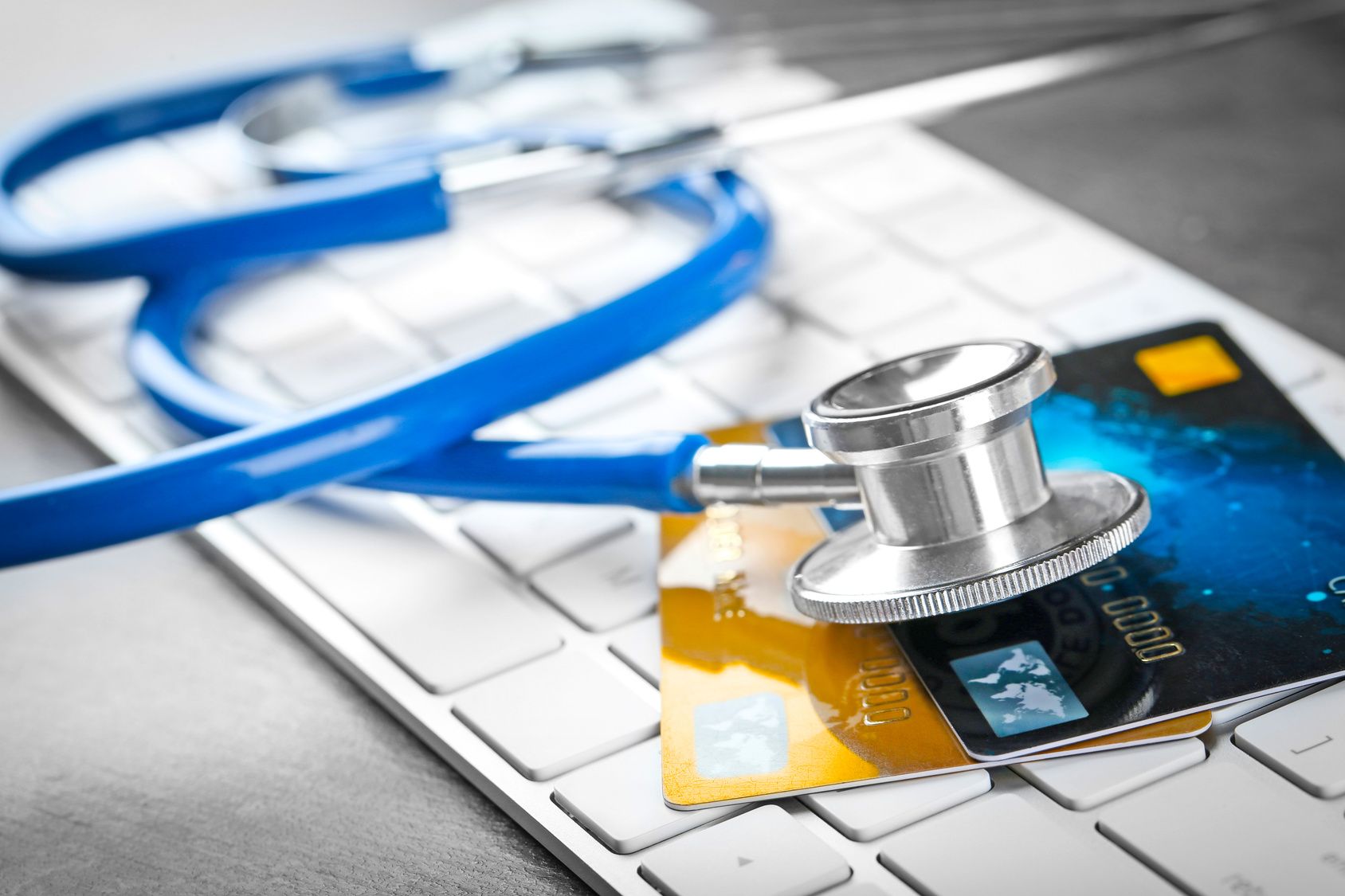 Stethoskop und Kreditkarten auf der Computertastatur, Nahaufnahme