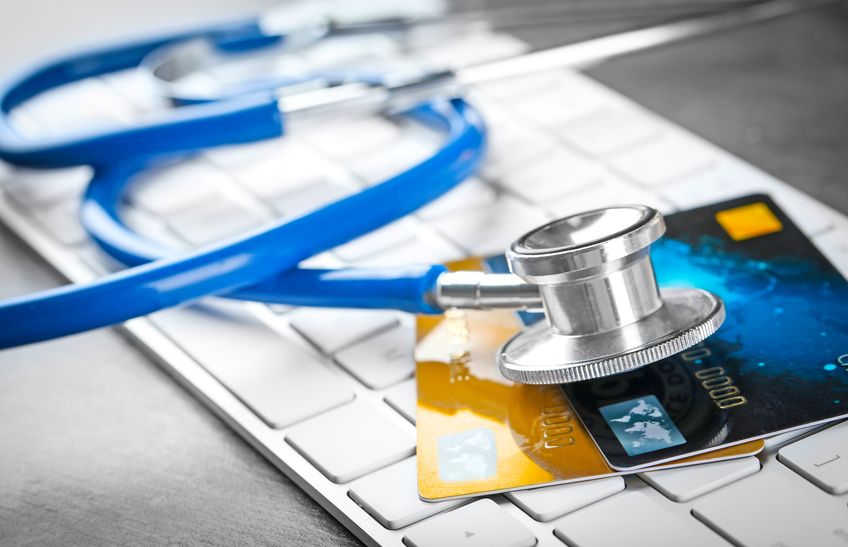 Stethoskop und Kreditkarten auf der Computertastatur, Nahaufnahme