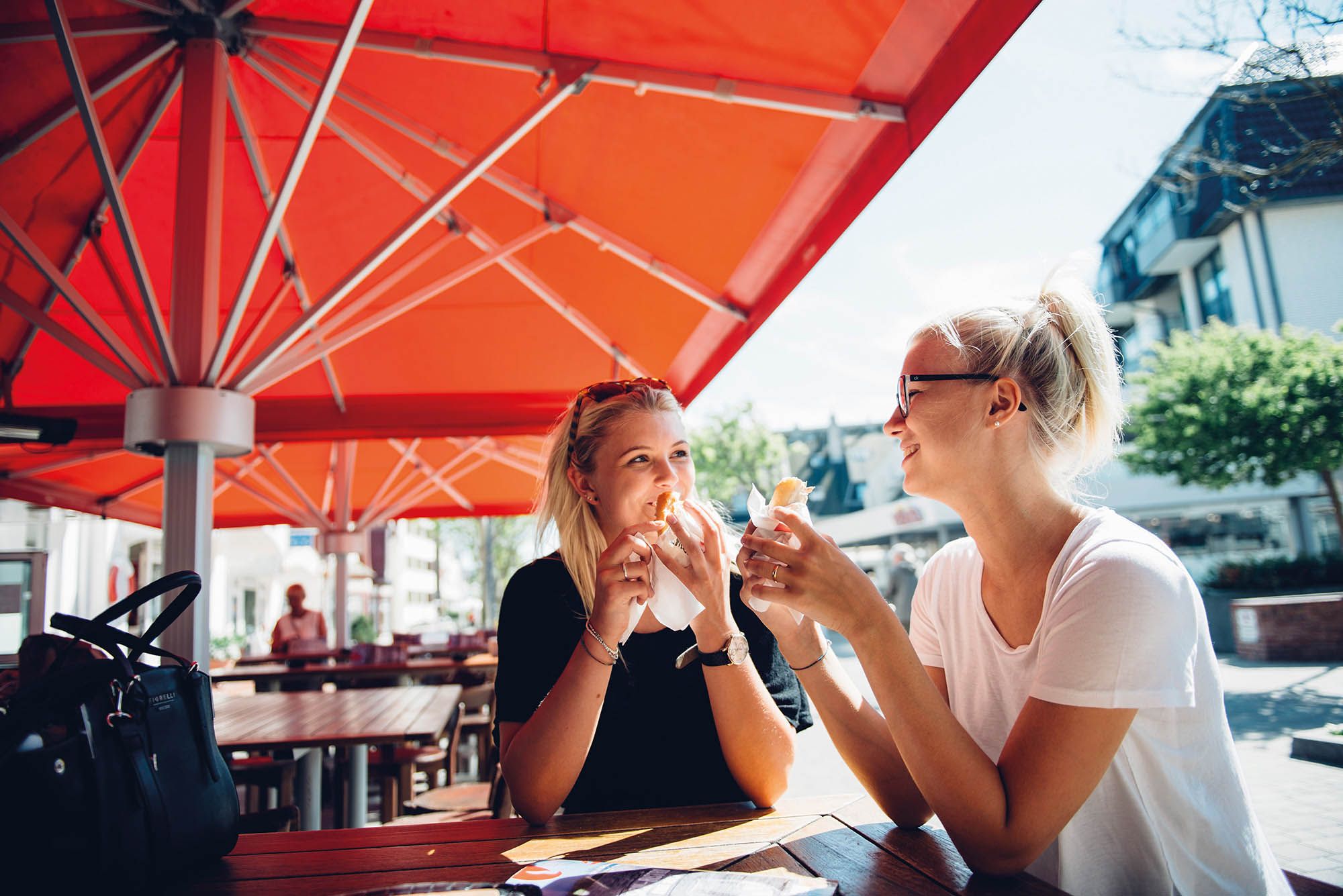 Zwei junge Frauen haben jeweils ein Fischbrötchen in der Hand