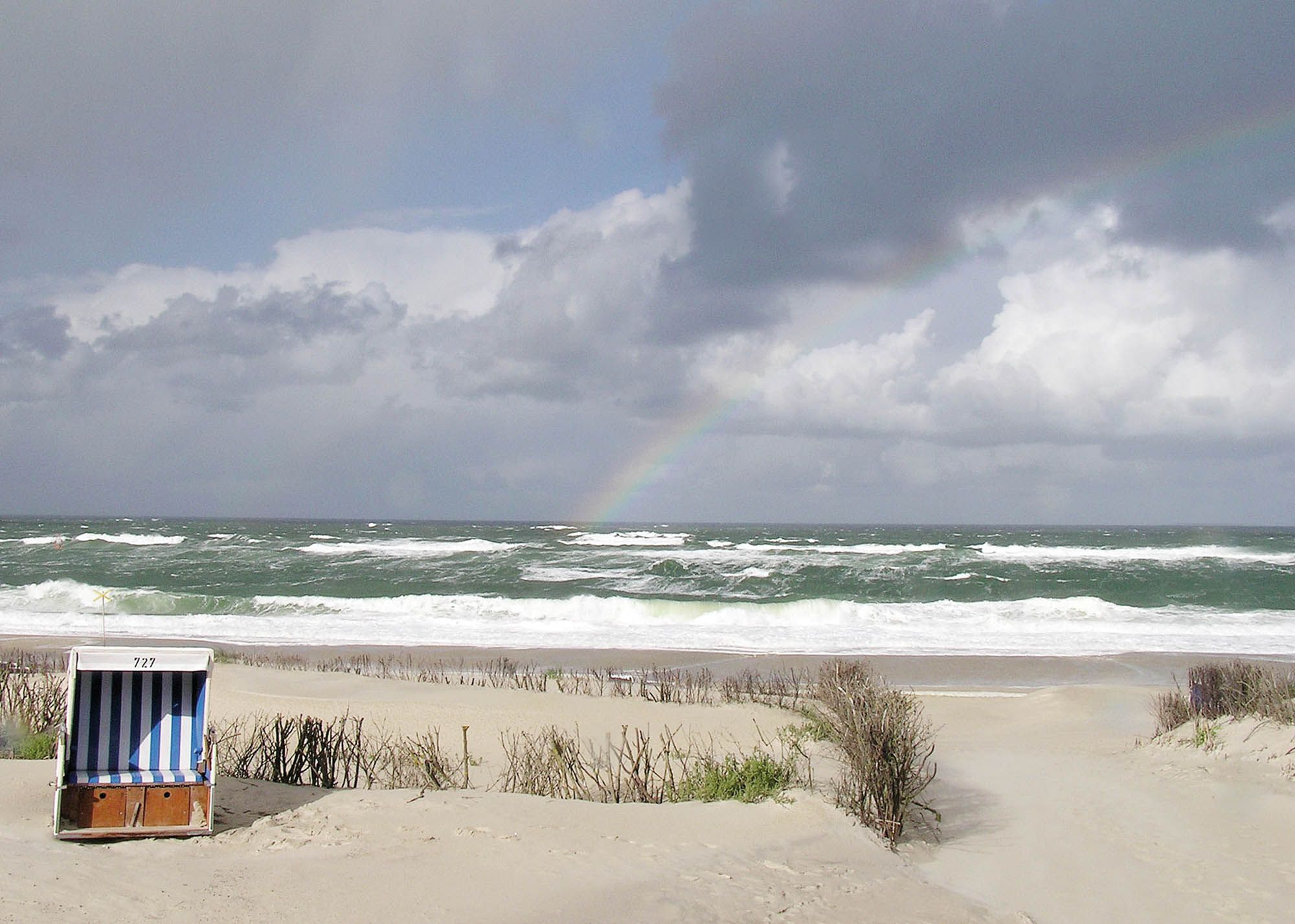 Regenbogen über der Nordsee und einzelner Strandkorb auf dem Weststrand in Westerland auf Sylt