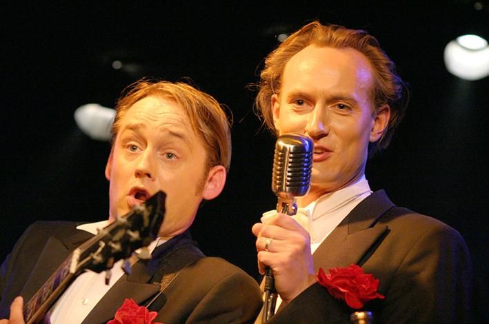 die beiden Mitglieder von Bidla Buh im Frack mit Mikrofon und Gitarre in der Hand