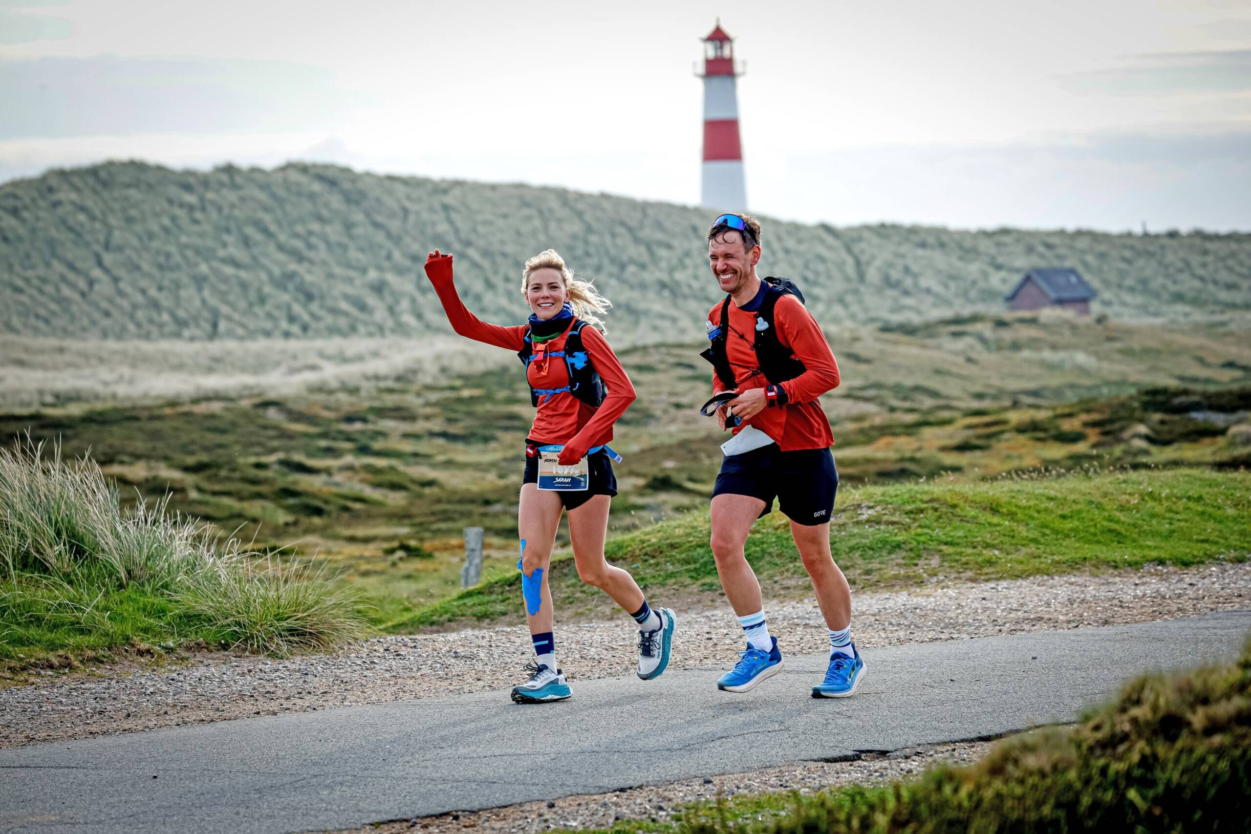 North Sea Ultra Marathon - 111km rund um die Insel laufen. Zwei Läufer vor einem Leuchtturm