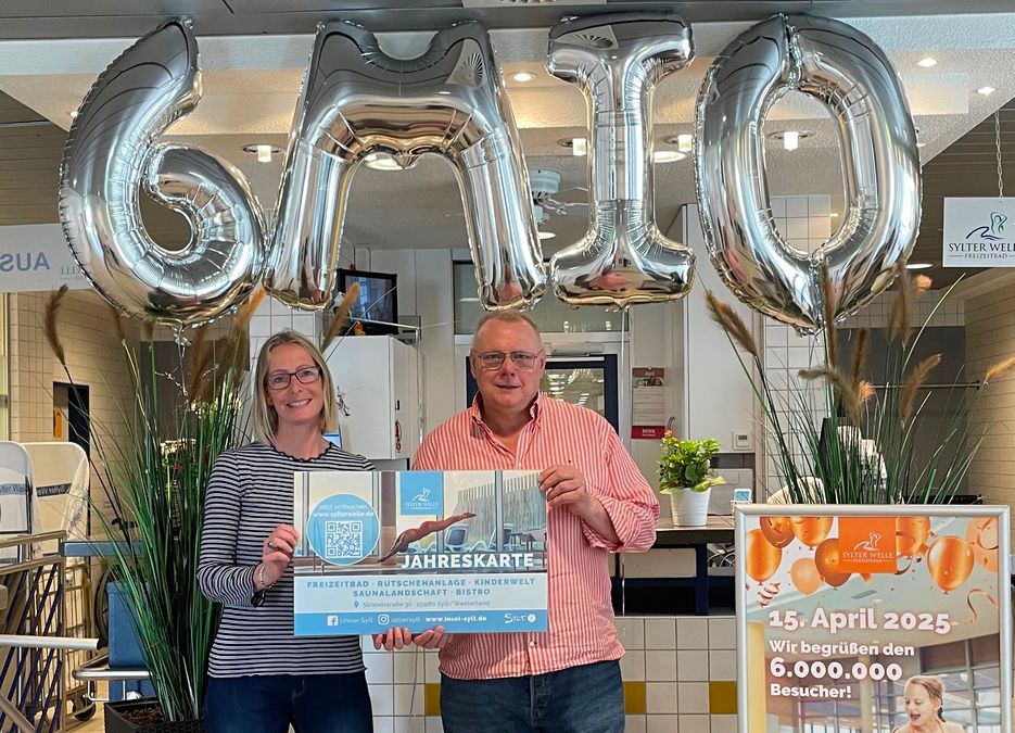 Preisübergabe beim sechs Millionsten Besucher der Sylter Welle. Zwei Personen stehen unter den 6 MIO Luftballons und halten den Gewinn in der Hand (XXL Jahreskarte für die Sylter Welle)