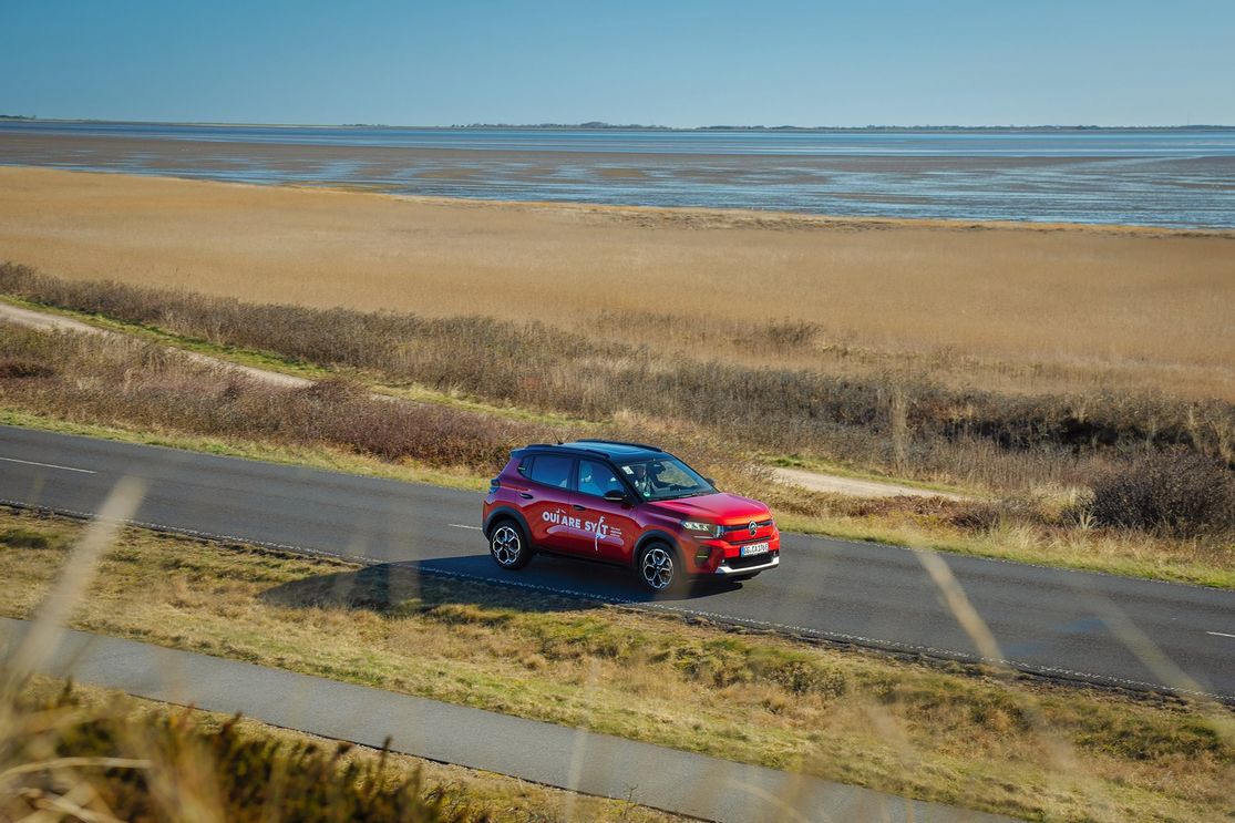 Roter Citroën e-C3 wurde im E-Mobility Center auf Sylt gemietet und fährt nun über Sylter Straßen mit dem Wattenmeer im Hintergrund