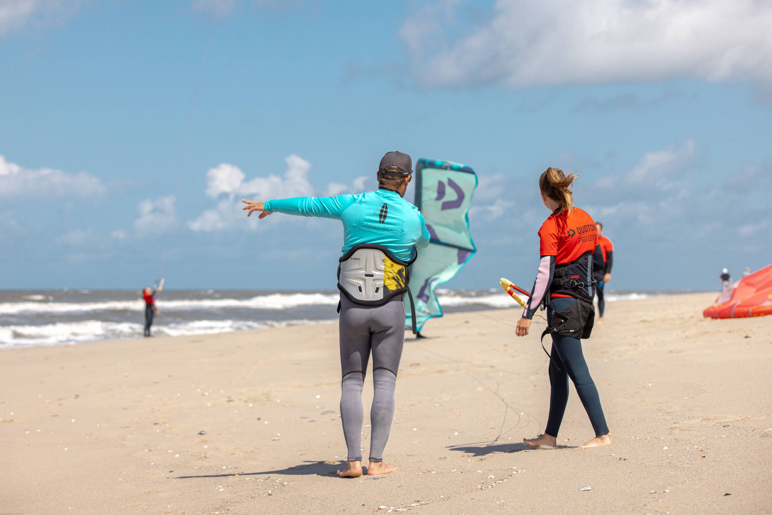 Zwei Menschen am Ufer mit Surfausstattung.