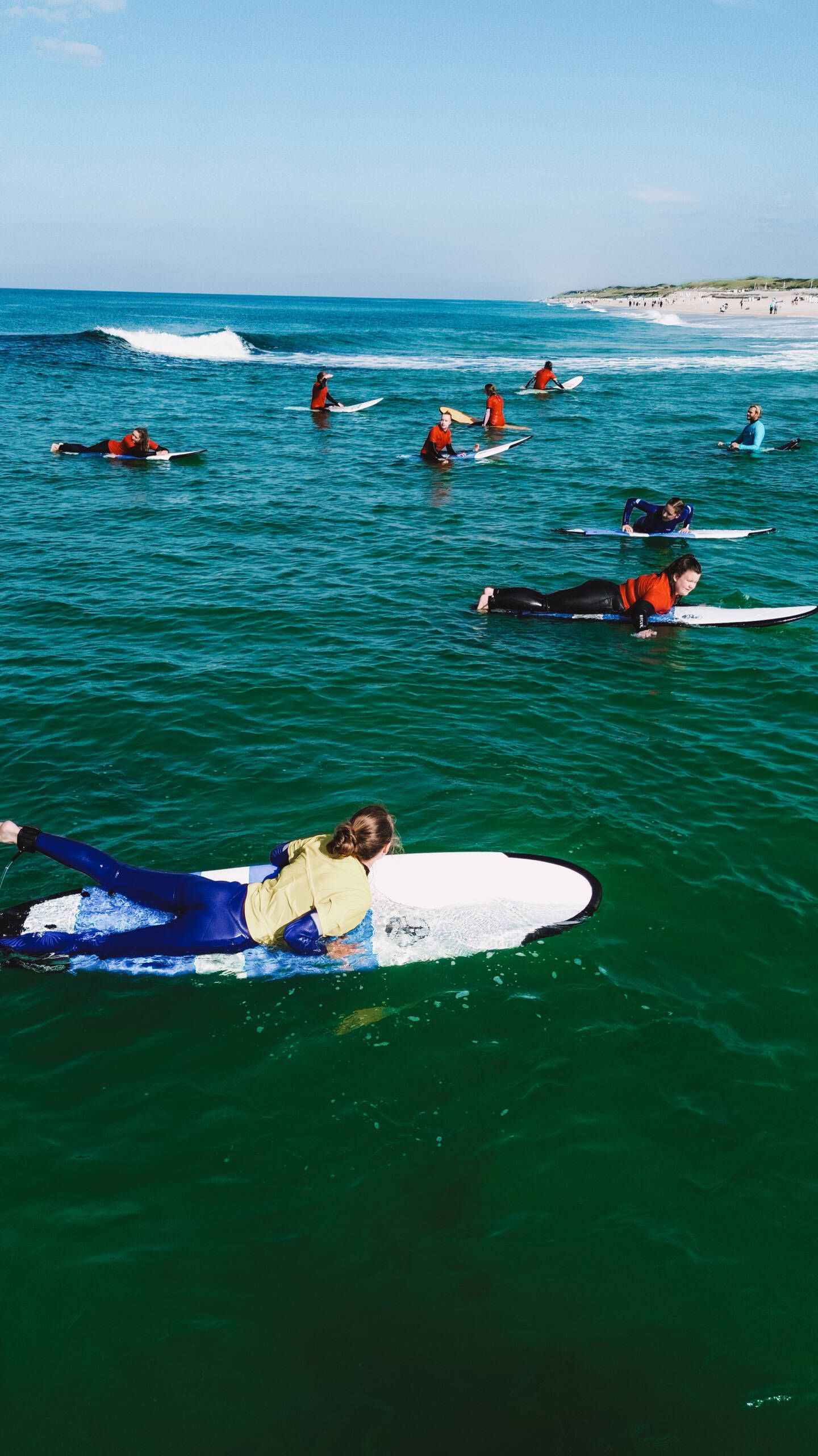 Mehrere Surfer, die im Wasser paddeln.