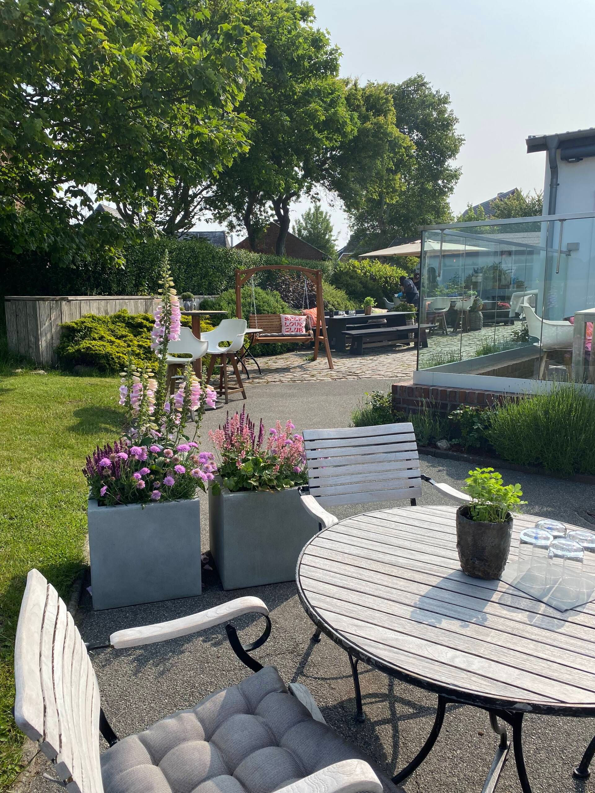 Außenterrasse mit bepflanztem Garten und Gartenmöbeln.