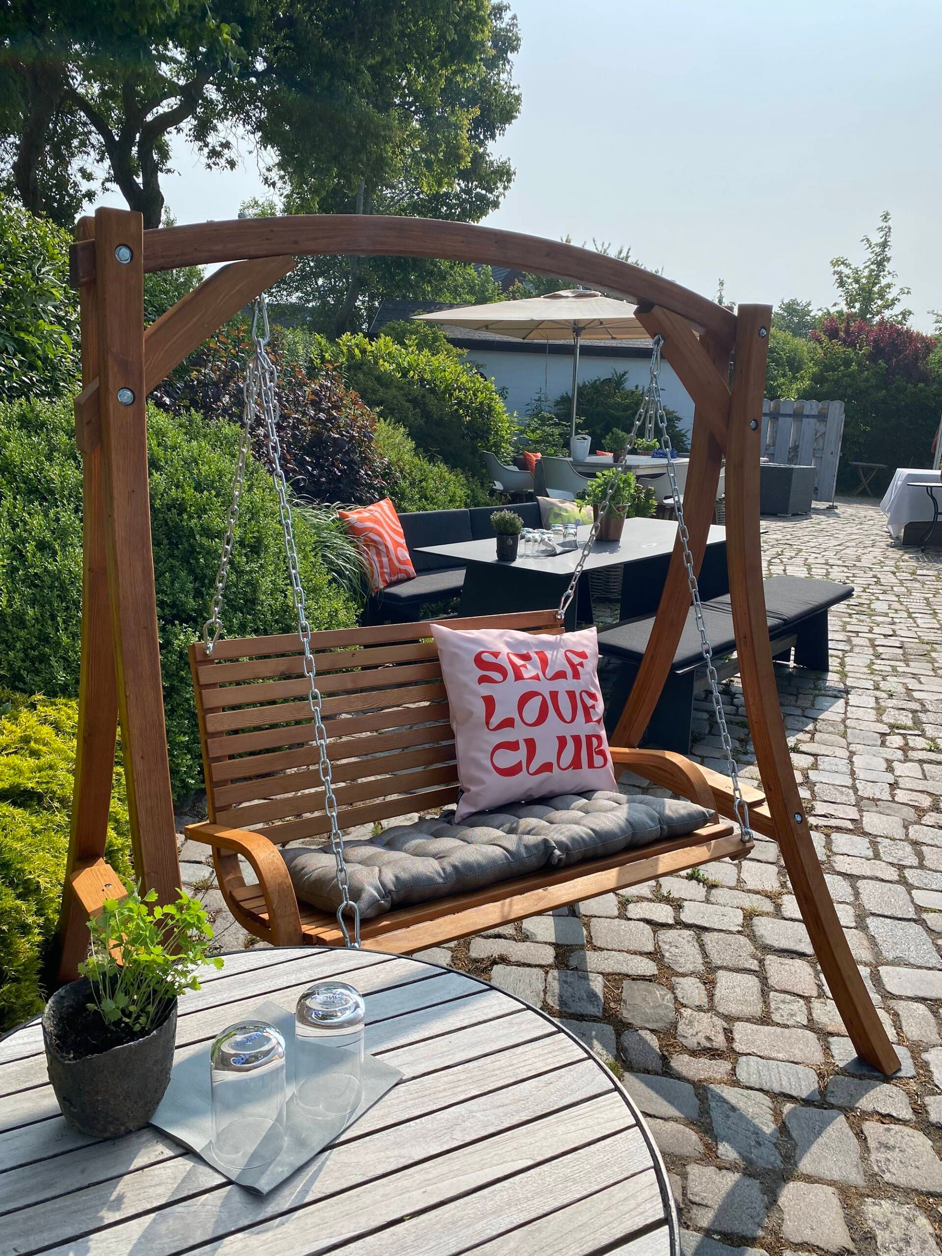 Außenbereich von Roots Sylt mit einer Gartenschaukel und einer Picknickbank.