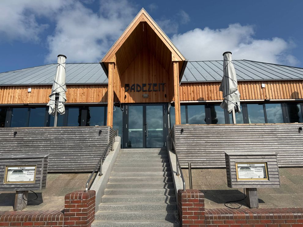Ein Außenfoto vom Strandrestaurant Badezeit zeigt das Gebäude mit der moderen Holzfassade