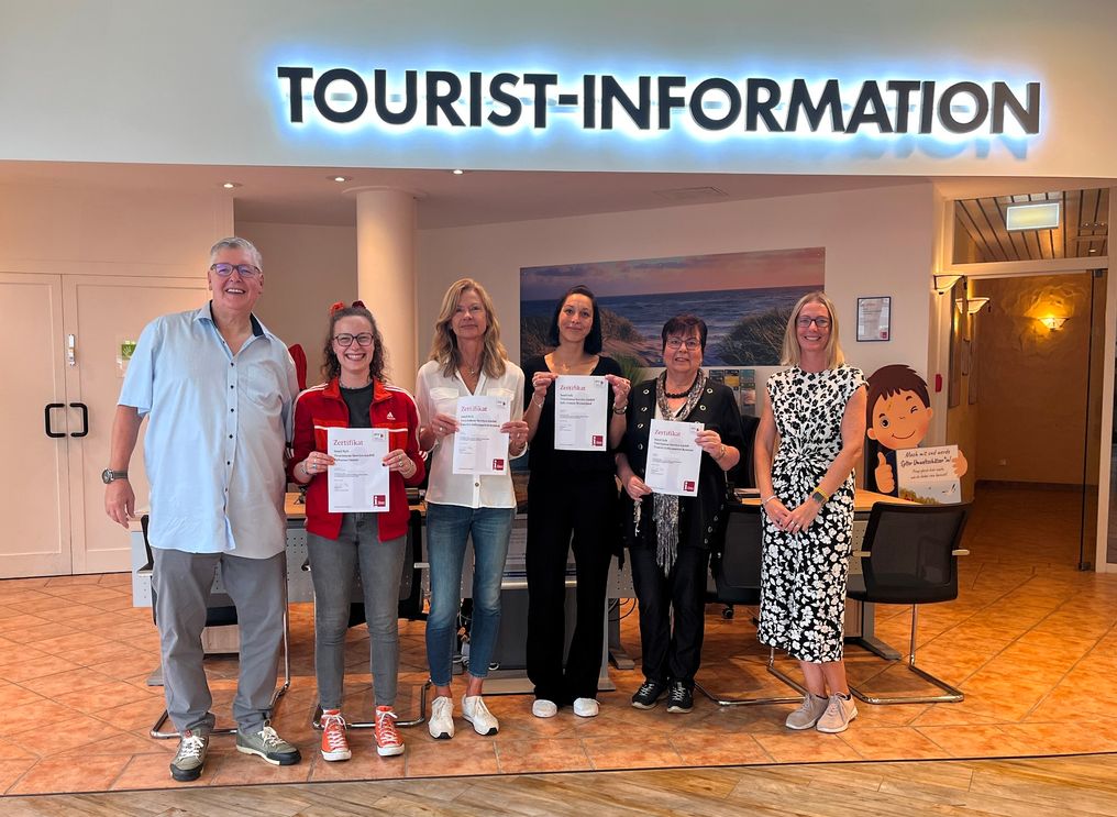 Sechs Mitarbeiter der Tourist-Informationen des Insel Sylt Tourismus-Service freuen sich über die neue Zertifizierung des DTV und halten die entsprechenden Urkunden hoch.