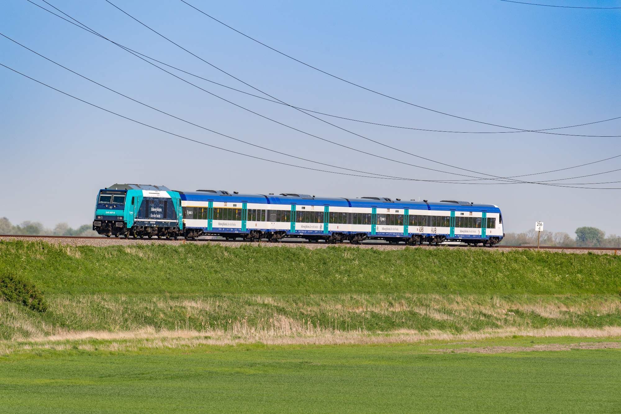 blau-weißer Nahverkehrszug der DB Regio auf dem Bahndamm nach Sylt