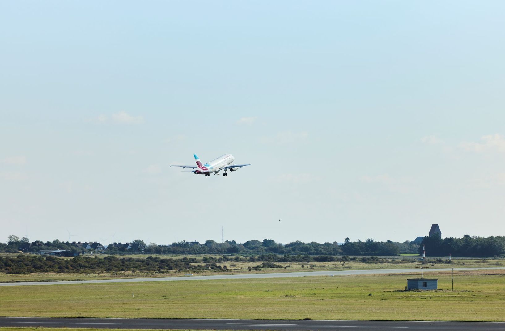 Flugzeug startet beim Flughafen Sylt und hebt vor der St. Severin Kirche in Keitum ab