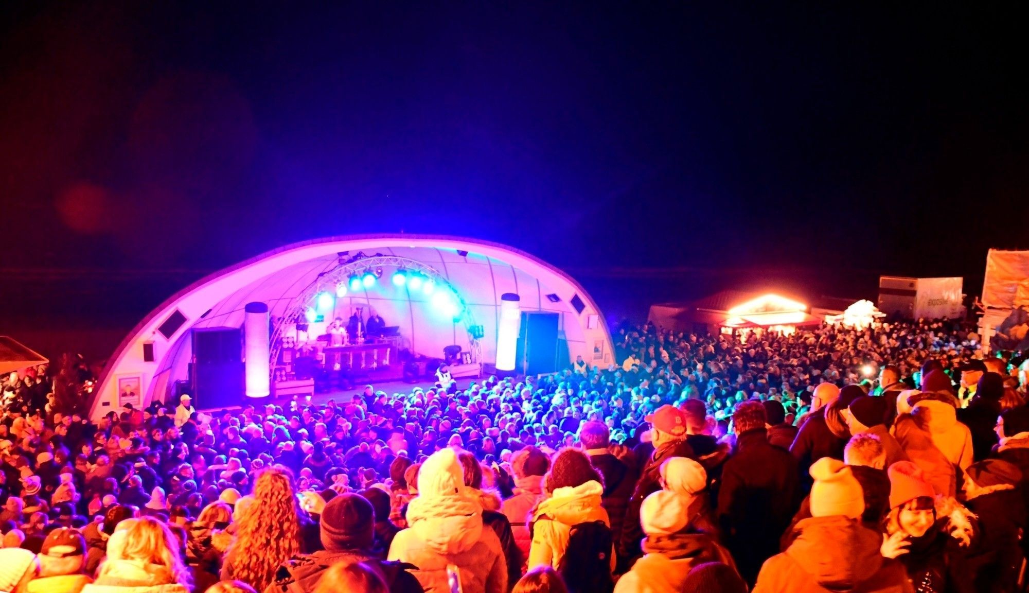 Hunderte Menschen feiern Silvester vor der Musikmuschel in Westerland während in eben dieser ein DJ Musik auflegt.
