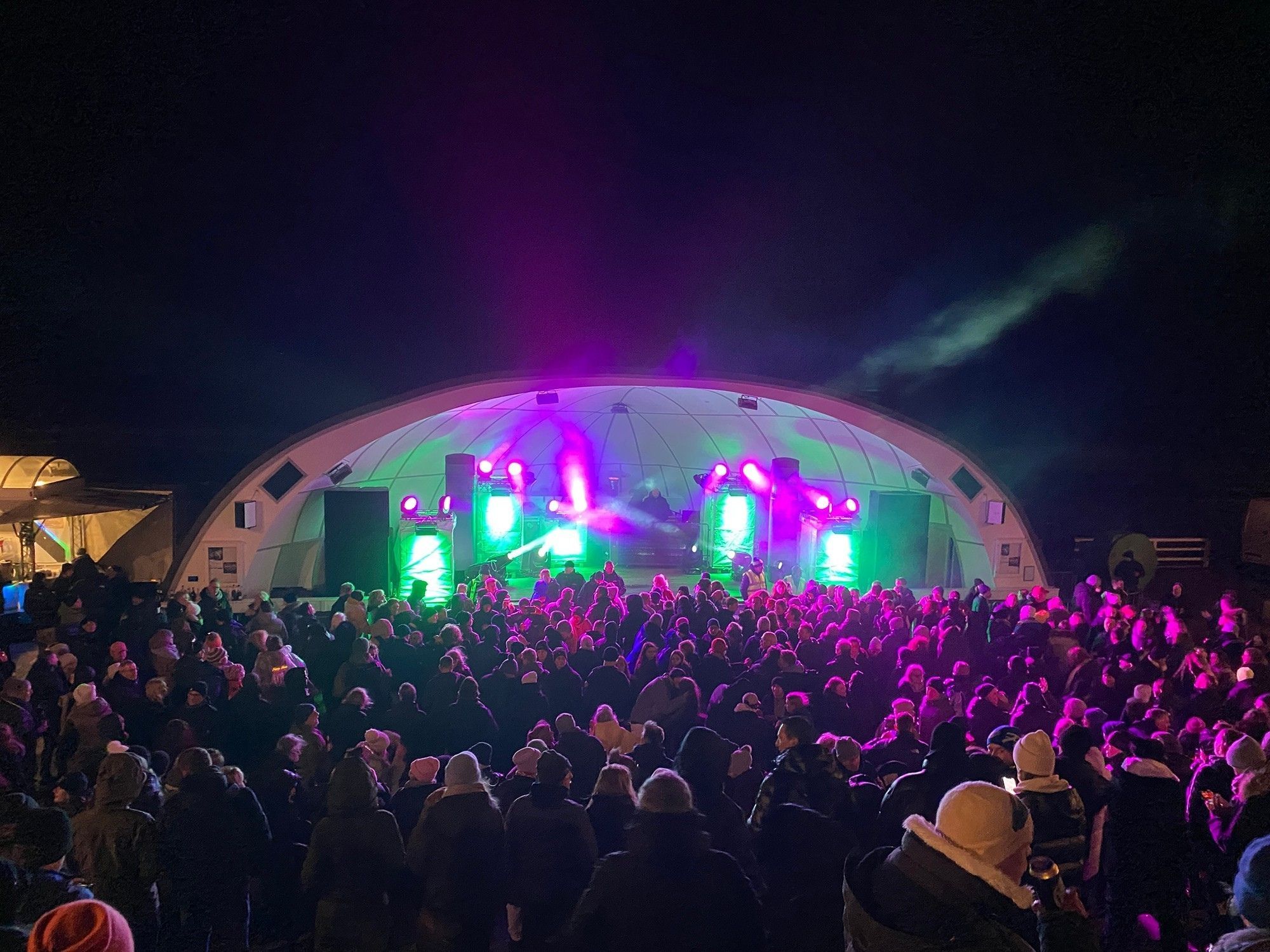 Hunderte Menschen feiern Silvester vor der Musikmuschel in Westerland während in eben dieser ein DJ Musik auflegt.