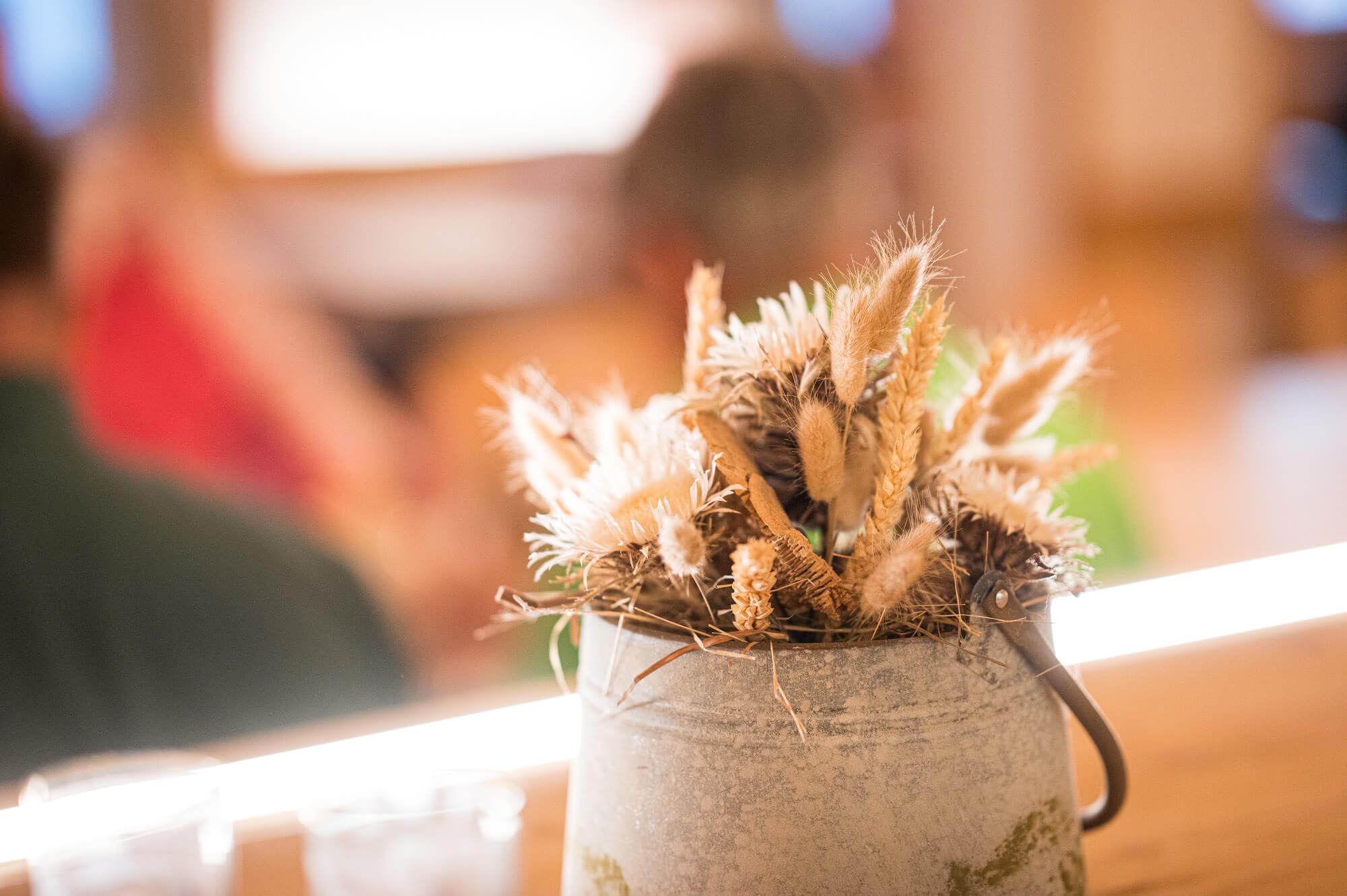 Trockenblumen in alter Metallkanne als Tischdeko.