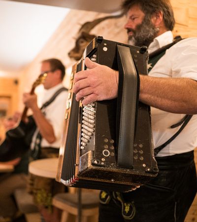 Zwei Musikanten in Tracht spielen Akkordeon und Gitarre im gemütlichen Gastraum.