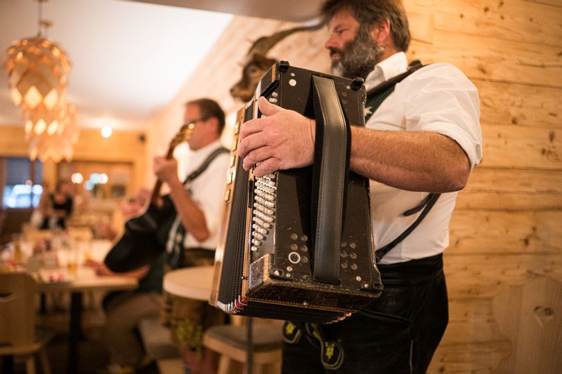 Zwei Musikanten in Tracht spielen Akkordeon und Gitarre im gemütlichen Gastraum.