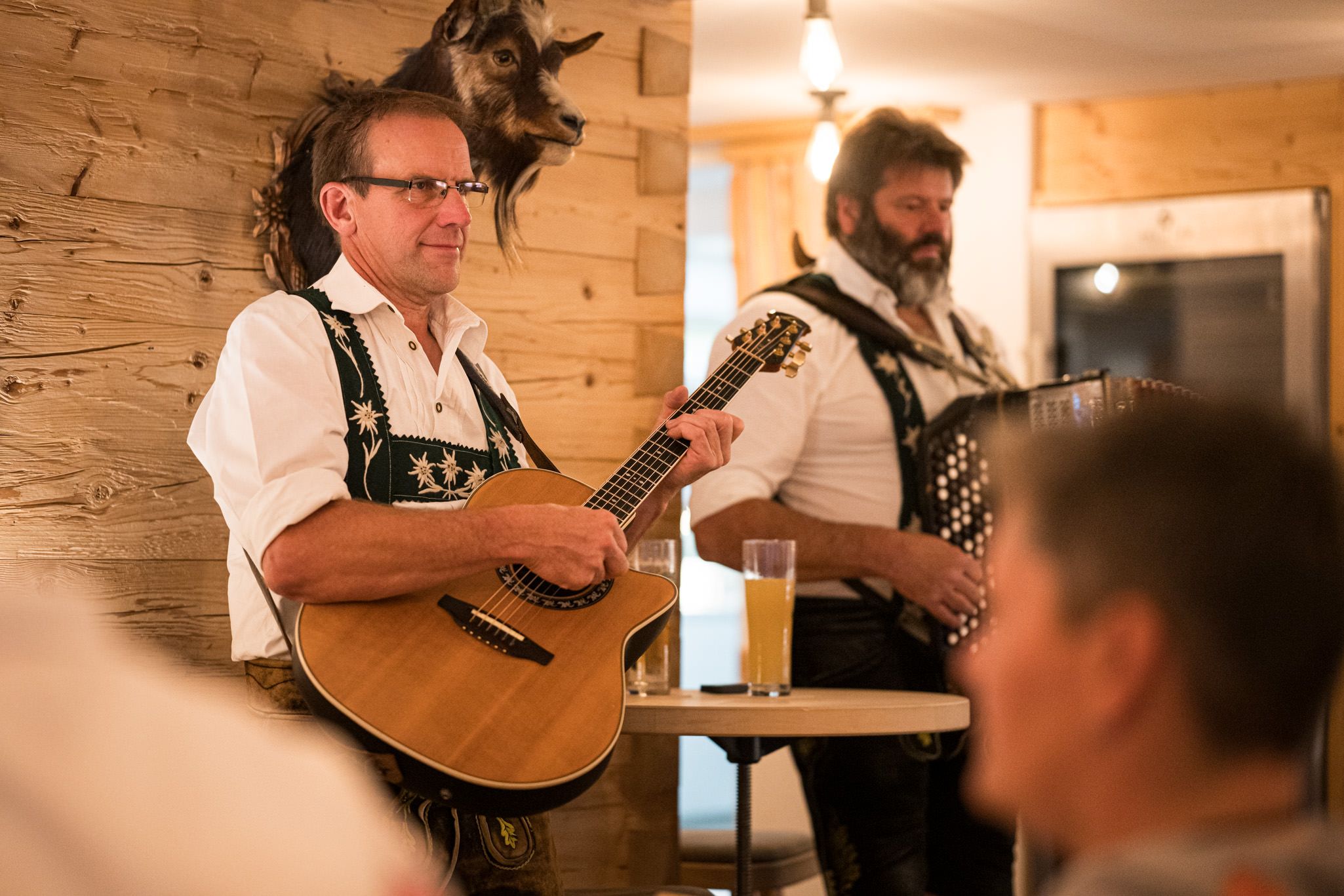 Zwei Musikanten in Tracht spielen Akkordeon und Gitarre im gemütlichen Gastraum.