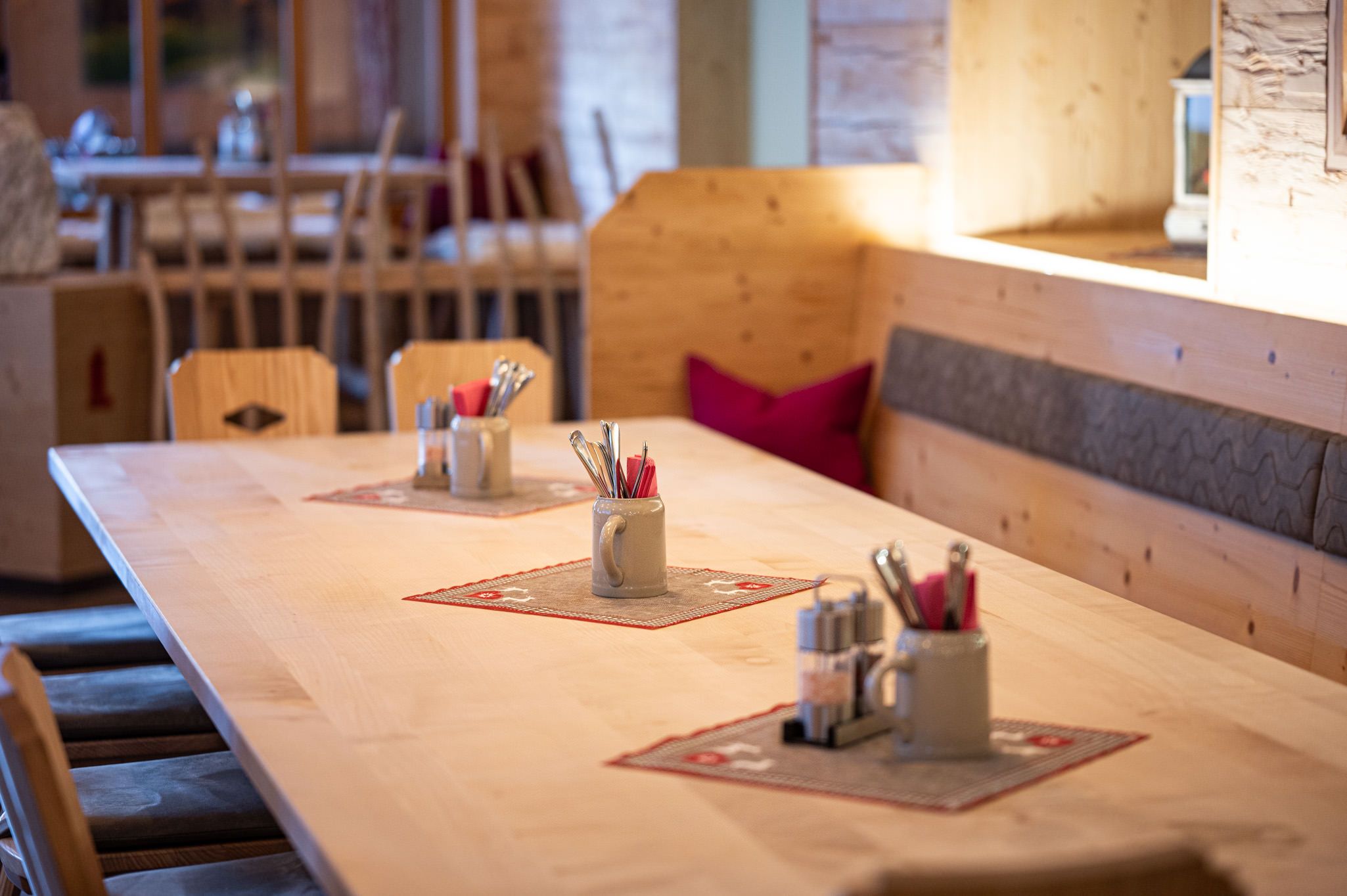 Gemütlich gedeckter Holztisch mit Besteckkrügen.