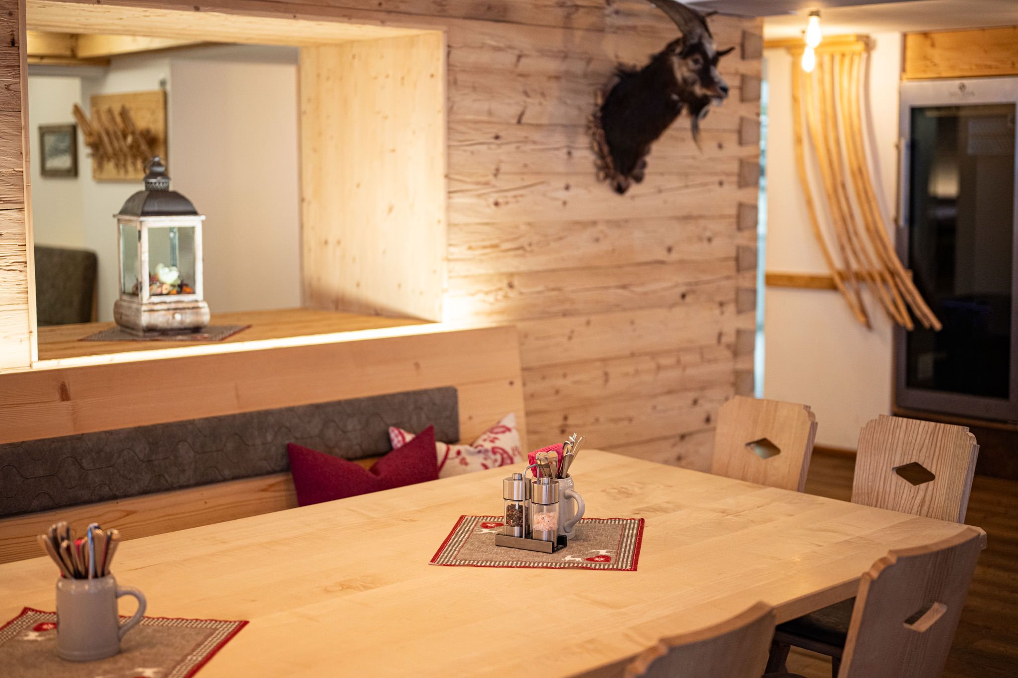 Gemütlich gedeckter Holztisch mit Besteckkrügen.