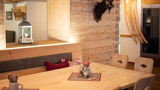 Gemütlich gedeckter Holztisch mit Besteckkrügen.