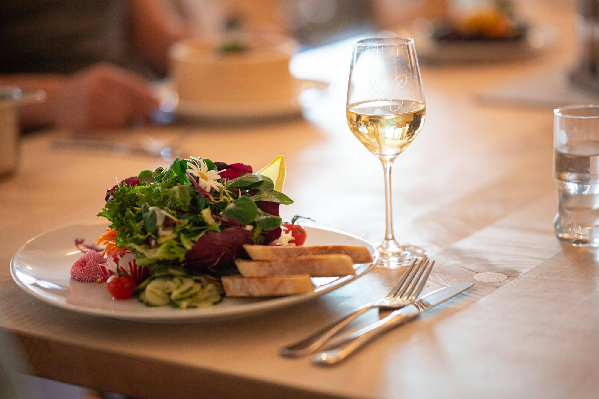 Frischer gemischter Salat mit Brot, dazu ein Glas Weißwein.